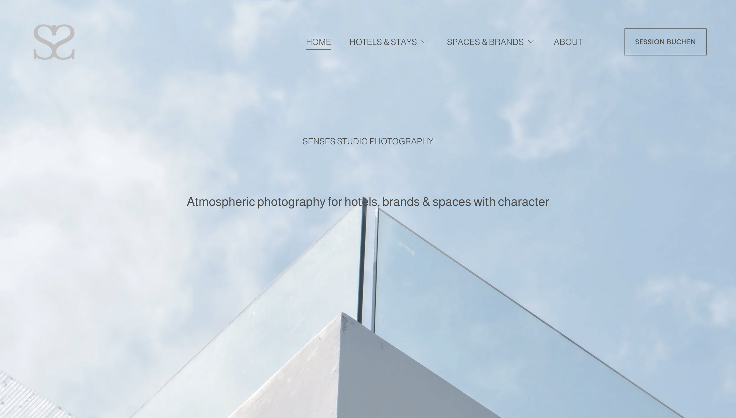 Webseite mit einer blauen Yogamatte auf Holzfußboden, darüber eine Hand, und Text, der Dienstleistungen wie Immobilien, Retreats, Architektur anbietet.