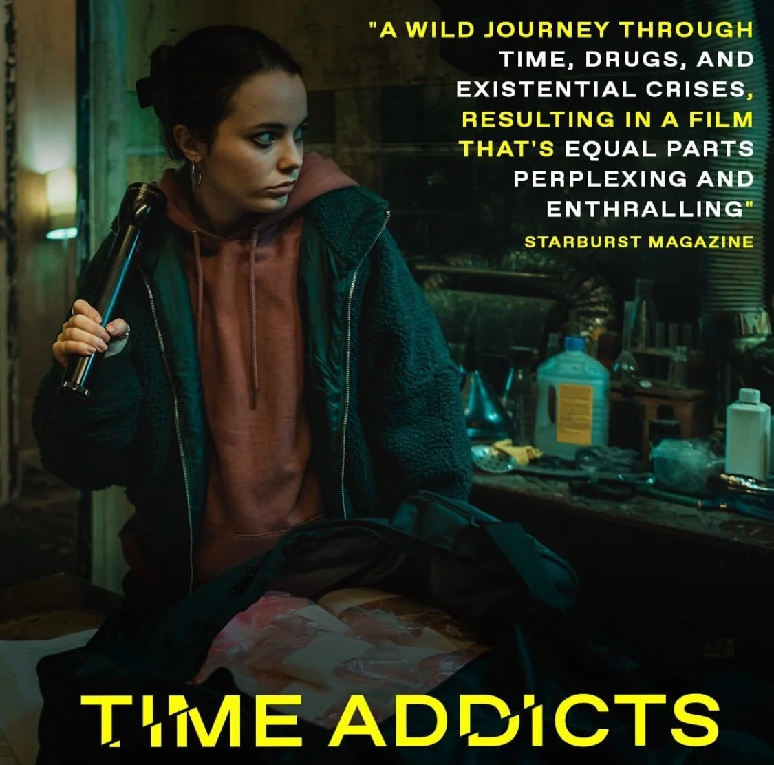 A young woman with dark hair tied back, holding a walkie-talkie, stands in a cluttered room with bottles and tools on a table. The room has a gritty, industrial feel with warm lighting. Overlaid text includes a quote from Starburst Magazine and the t