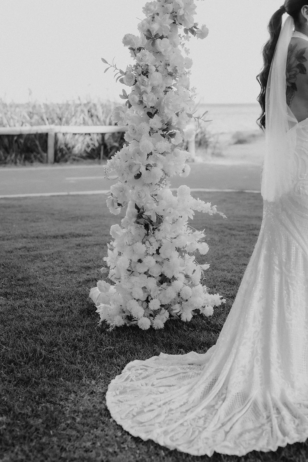 Bride with long dark hair standing in front of a wedding flower arbour at Whalers Cove in DUNSBOROUGH W.A at her elopement 