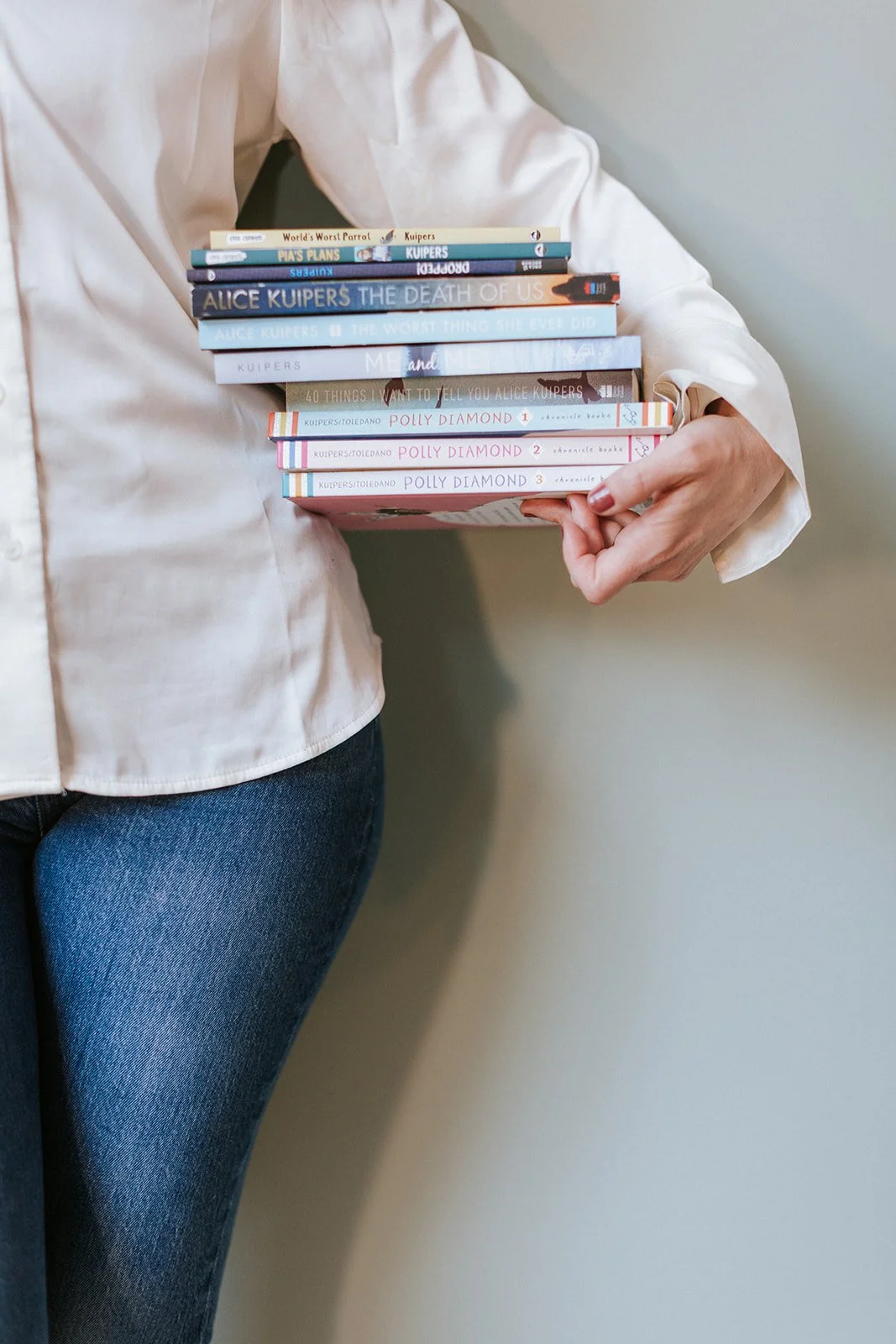 Alice Kuipers author holding a stack of her books