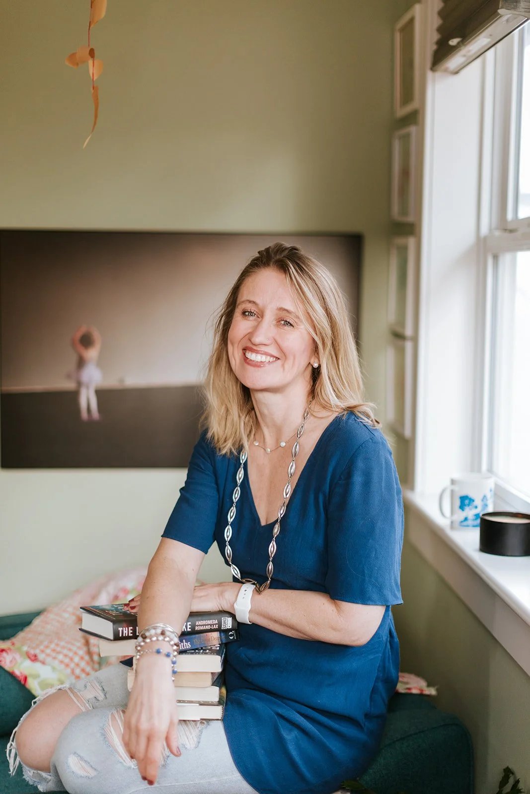Alice Kuipers sitting smiling with pile of books on her lap