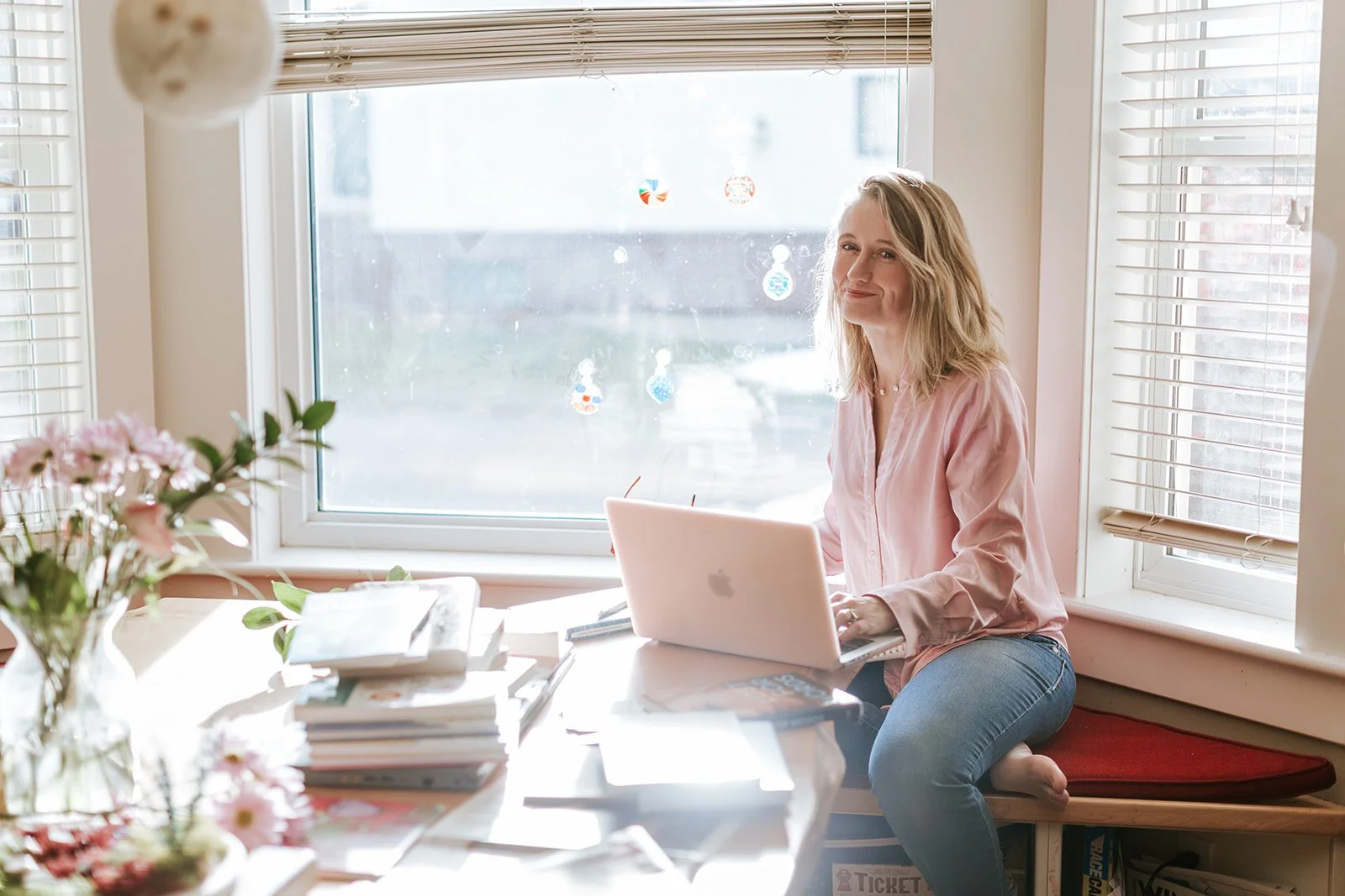 Alice Kuipers Author sitting in front of laptop with pile of books on table
