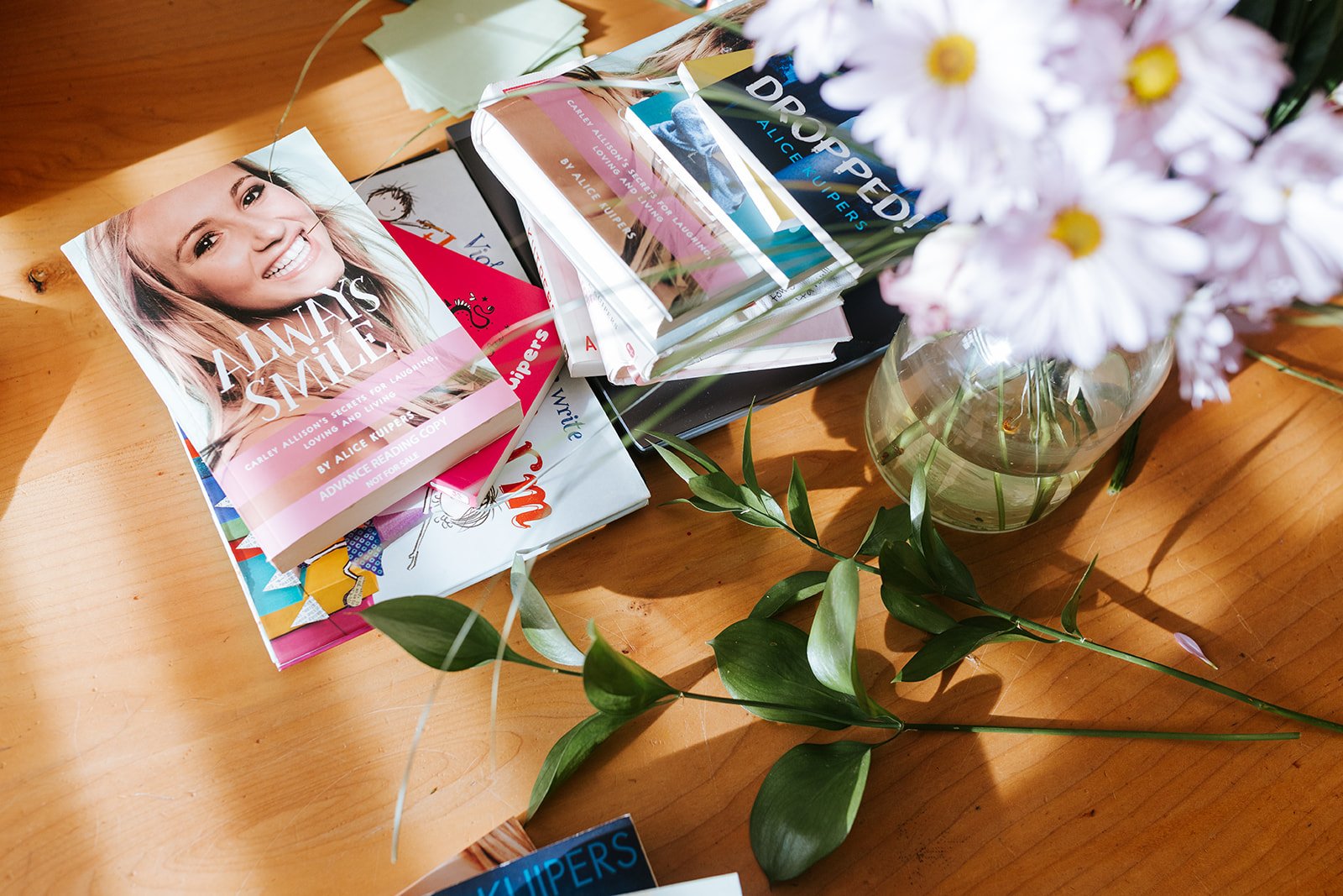 Alice Kuipers author books on table beside foliage