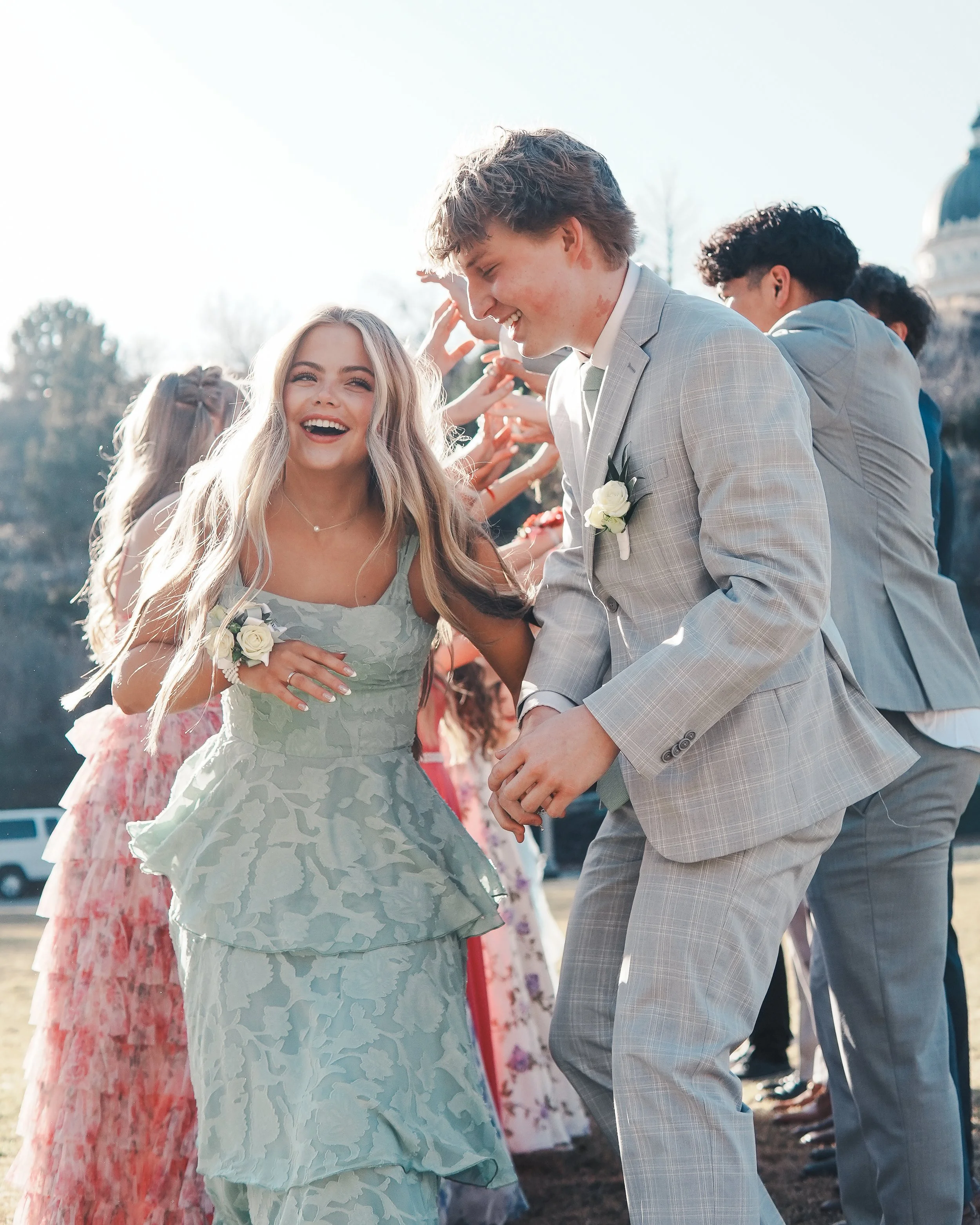 People dancing and laughing at a wedding reception outdoors on a sunny day.