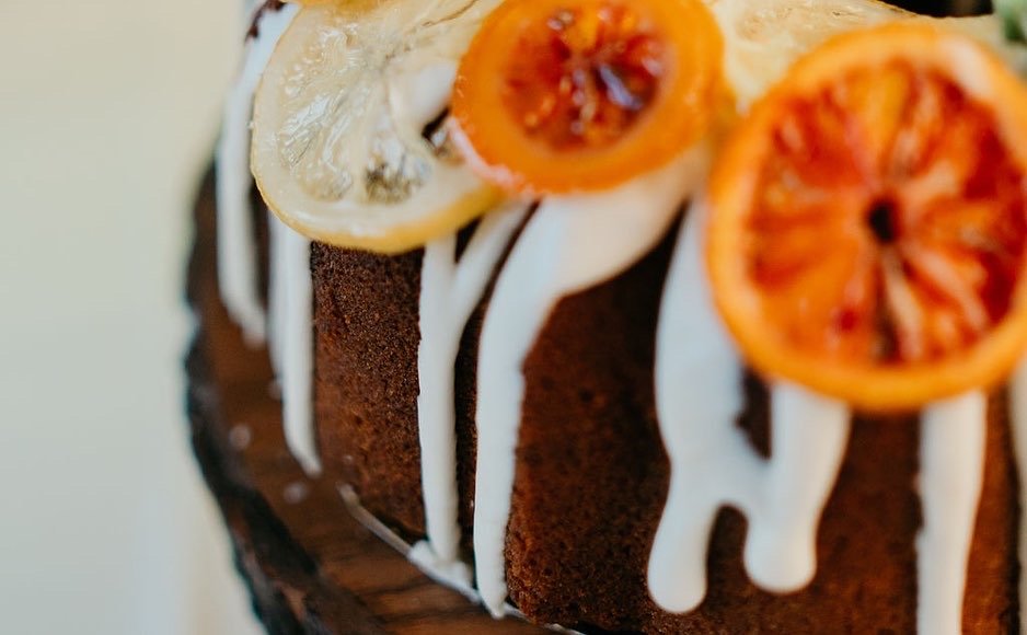 Close-up of a chocolate cake topped with lemon and orange slices, with white icing drizzled over the top. Unique wedding cake. 