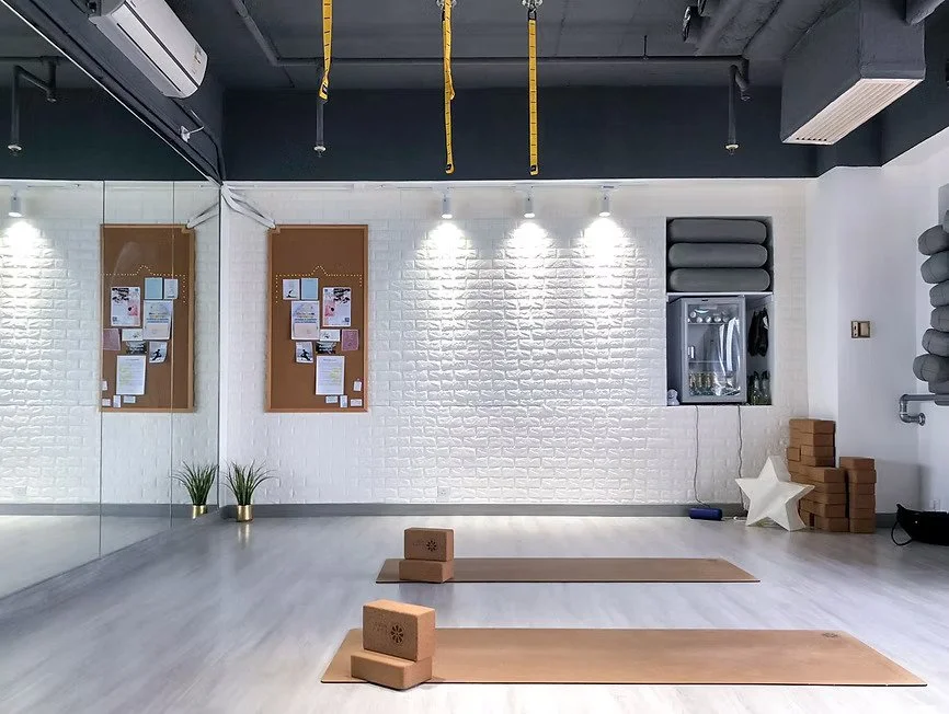 Yoga studio with two mats, yoga blocks, wall mirrors, bulletin boards, and decor.