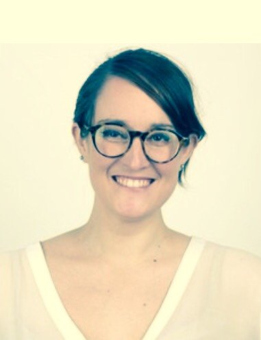 A woman with short dark hair, glasses, and a white top smiling at the camera.