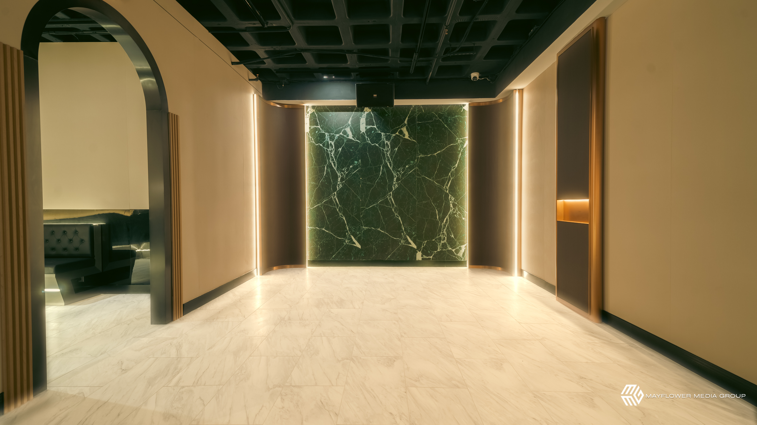 Modern interior hallway with green marble wall, beige walls, black ceiling, and marble floor.