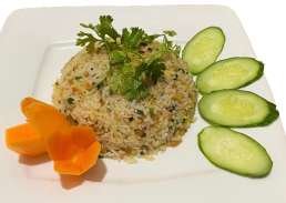 Fried rice garnished with cilantro, served with sliced cucumber, carrots, and a small piece of carved vegetable