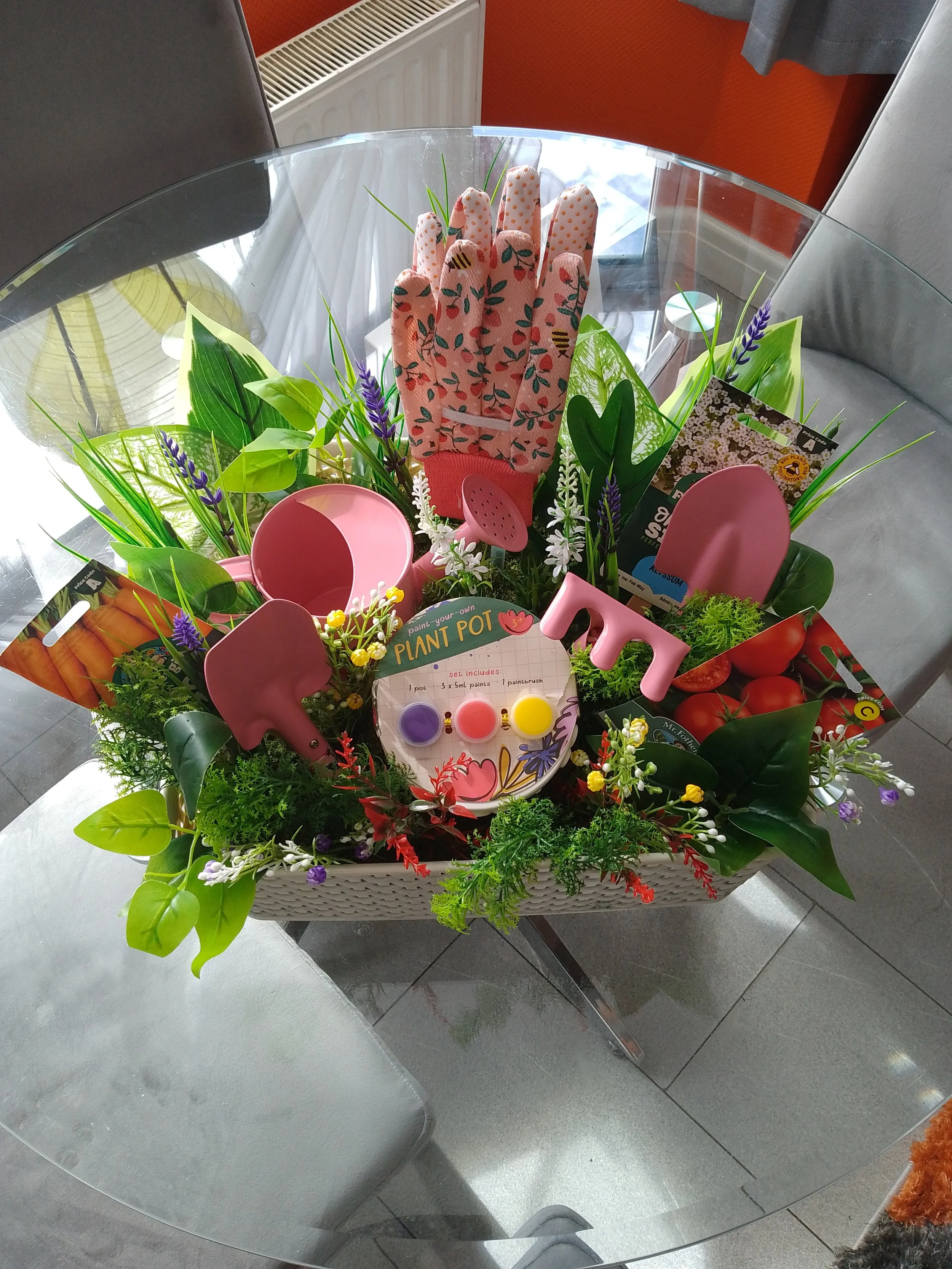 Colorful gardening kit with a glove, plant pots, gardening tools, and decorative letters spelling 'LOVE' arranged with flowers and soil, suitable for decorating or planting.