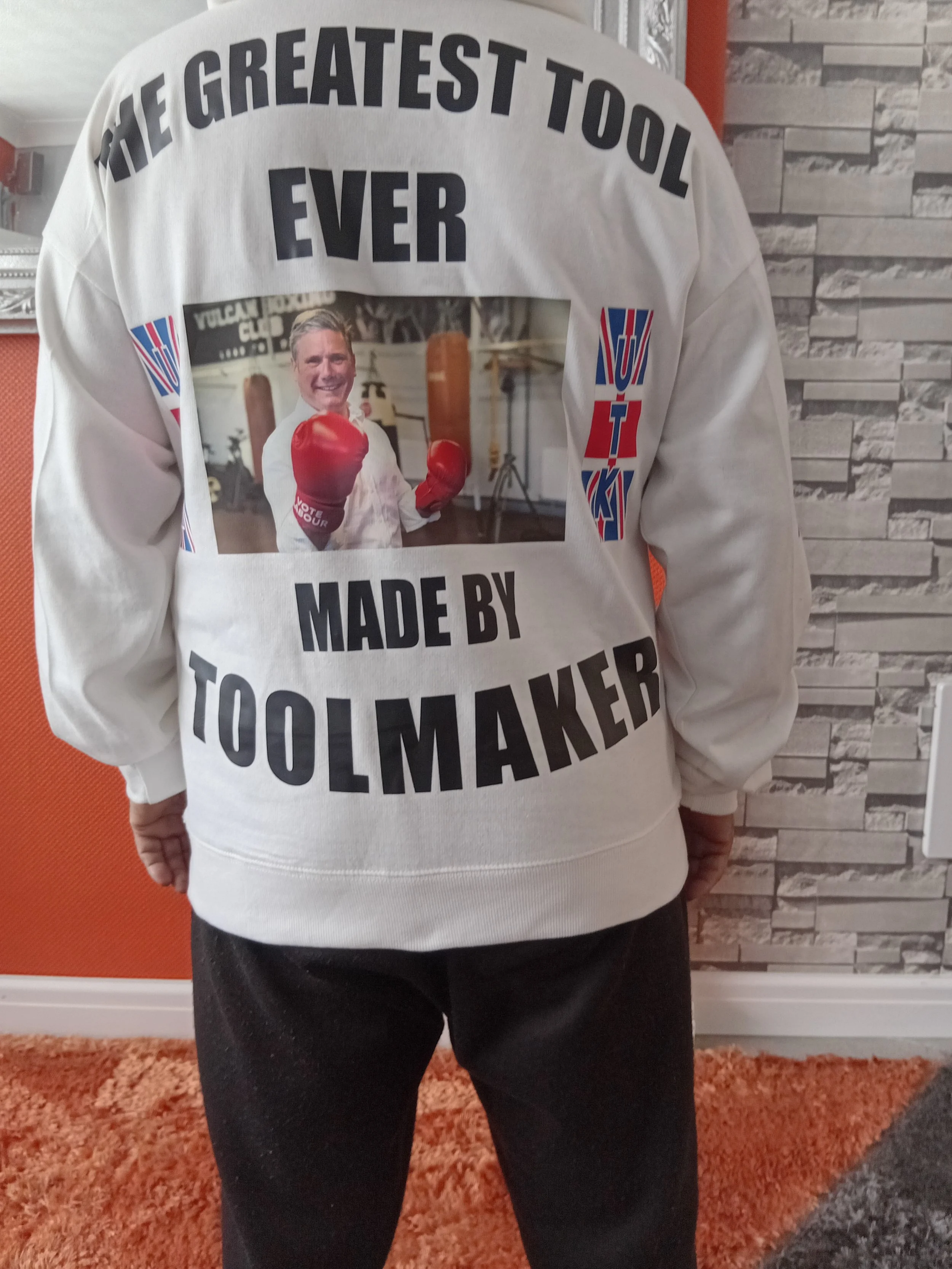Back of a person wearing a white sweatshirt with a photo of a man with boxing gloves and the words 'The greatest tool ever made by toolmaker' printed on it.