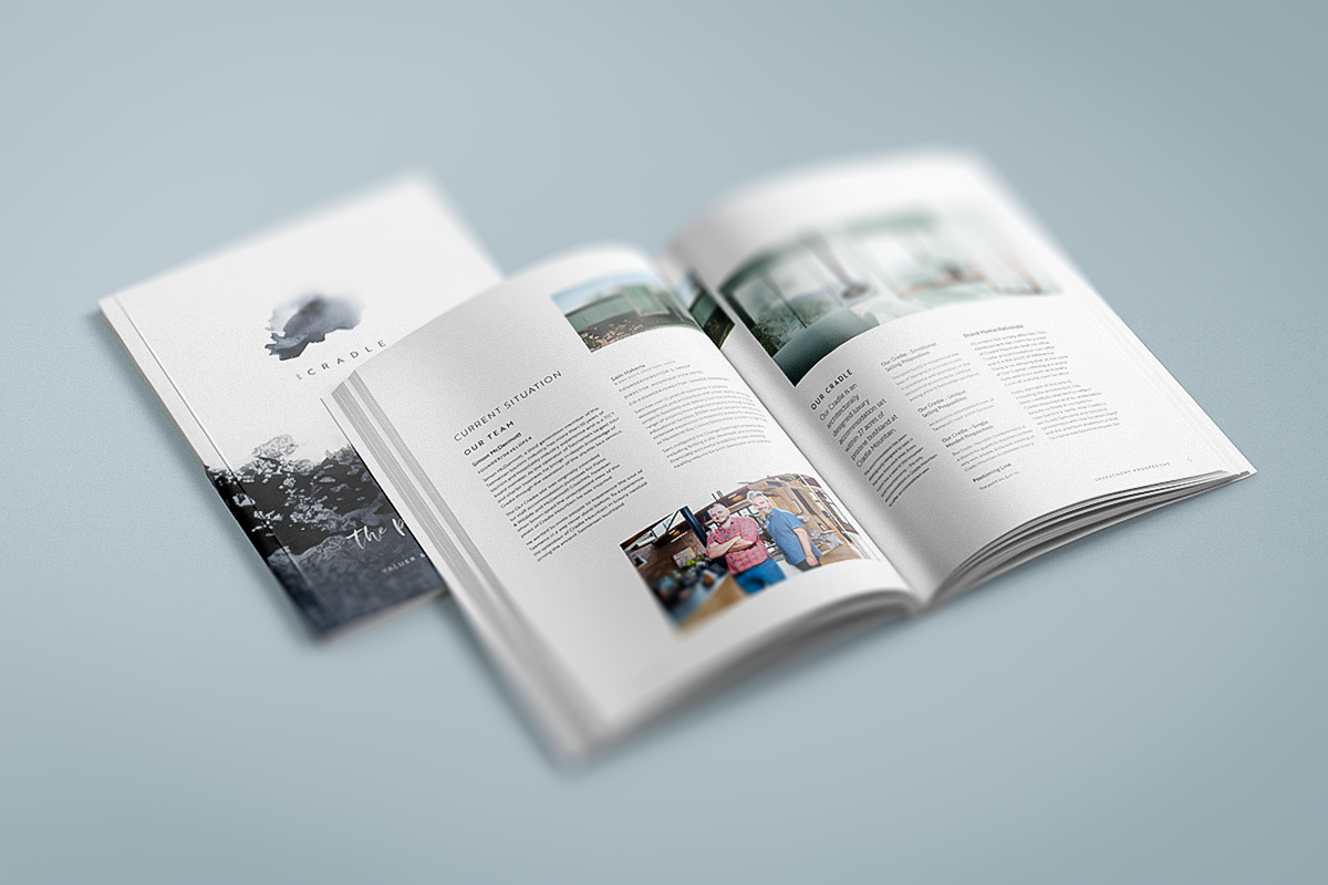 Open prospectus document with pages displaying text, images, and a the logo of the Our Cradle development, on a light-colored surface.