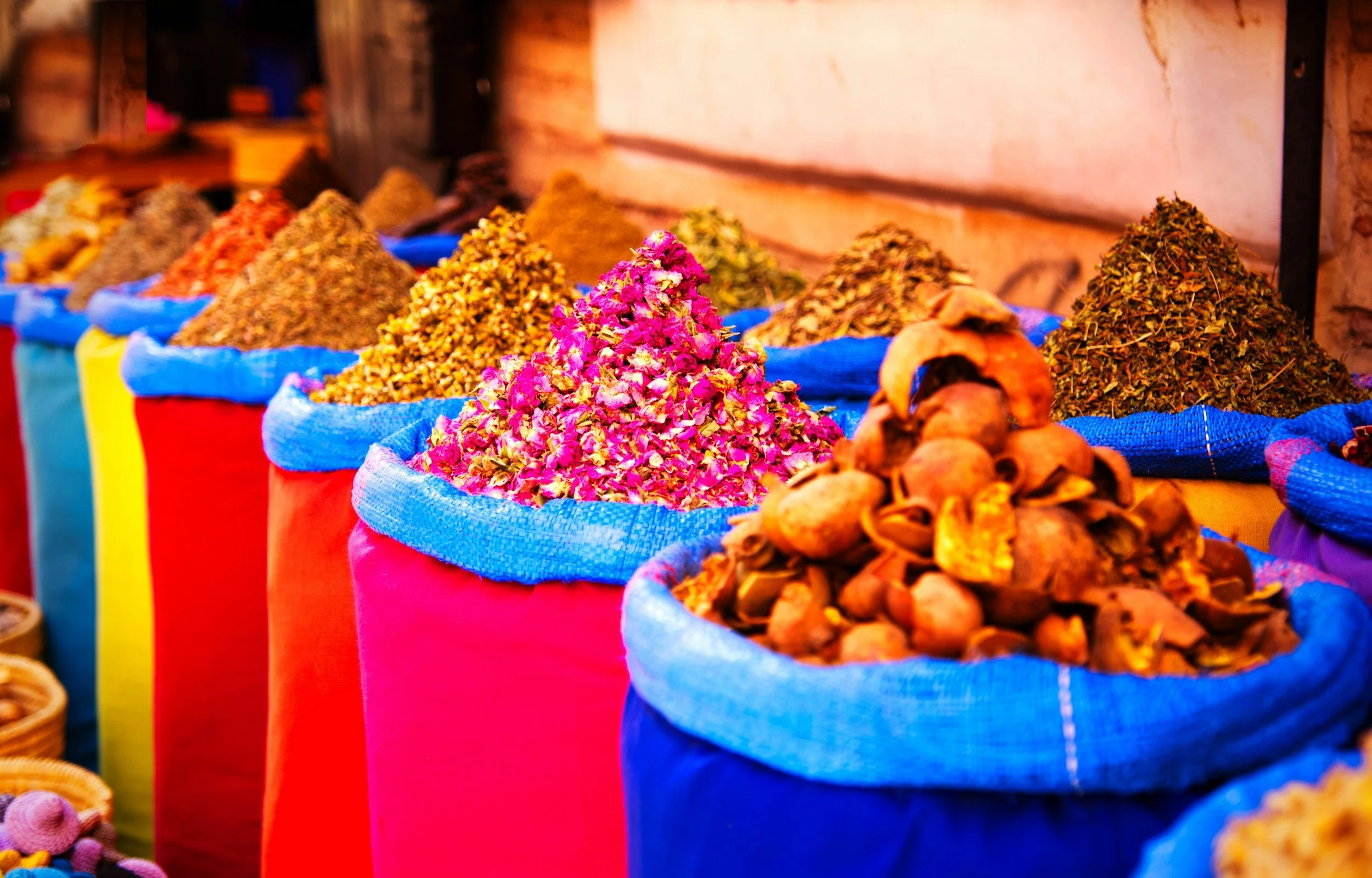 Colorful sacks filled with dried herbs, flowers, and spices at an outdoor market.