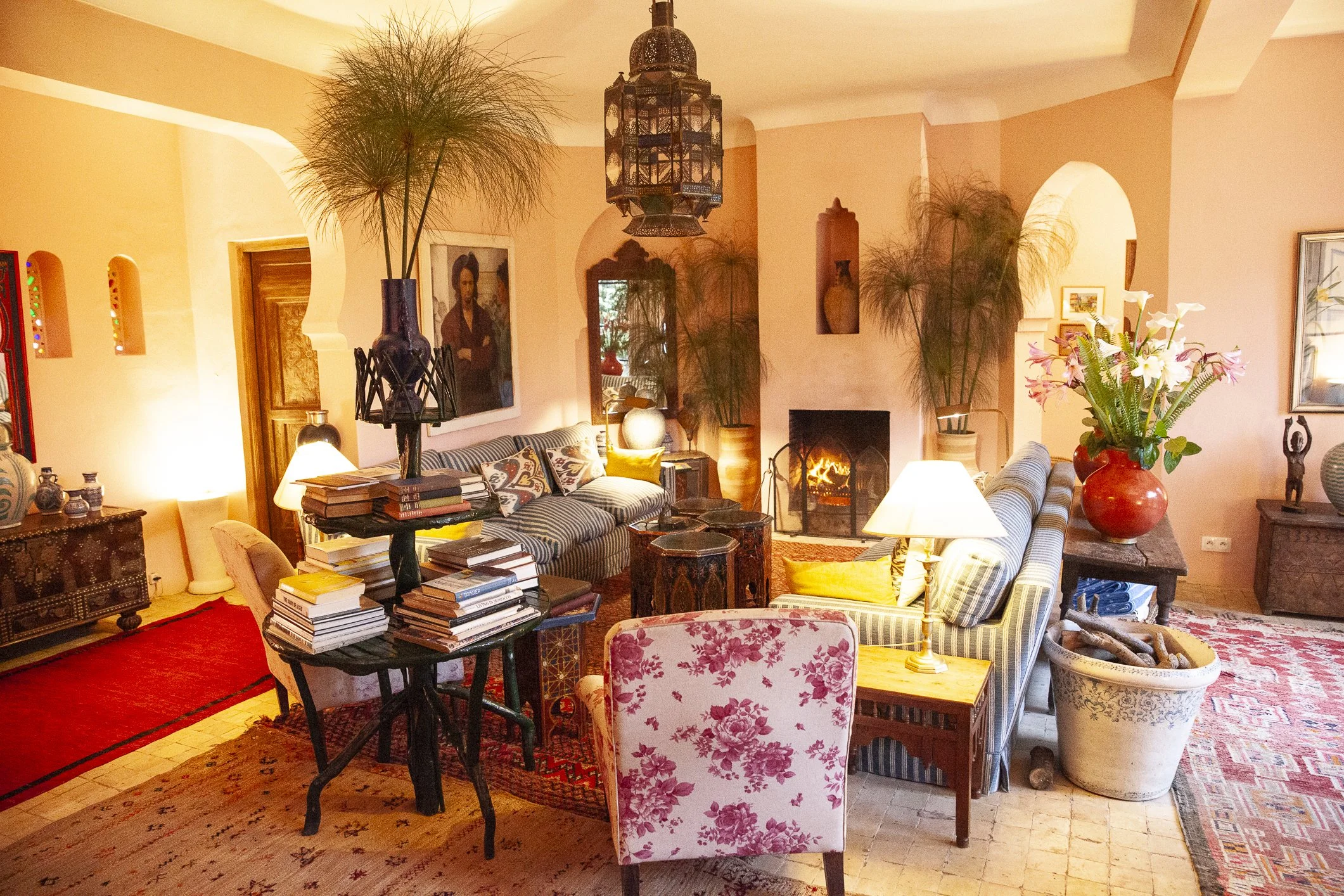A cozy living room with sofas, a fireplace, plants, lamps, and decorative items.