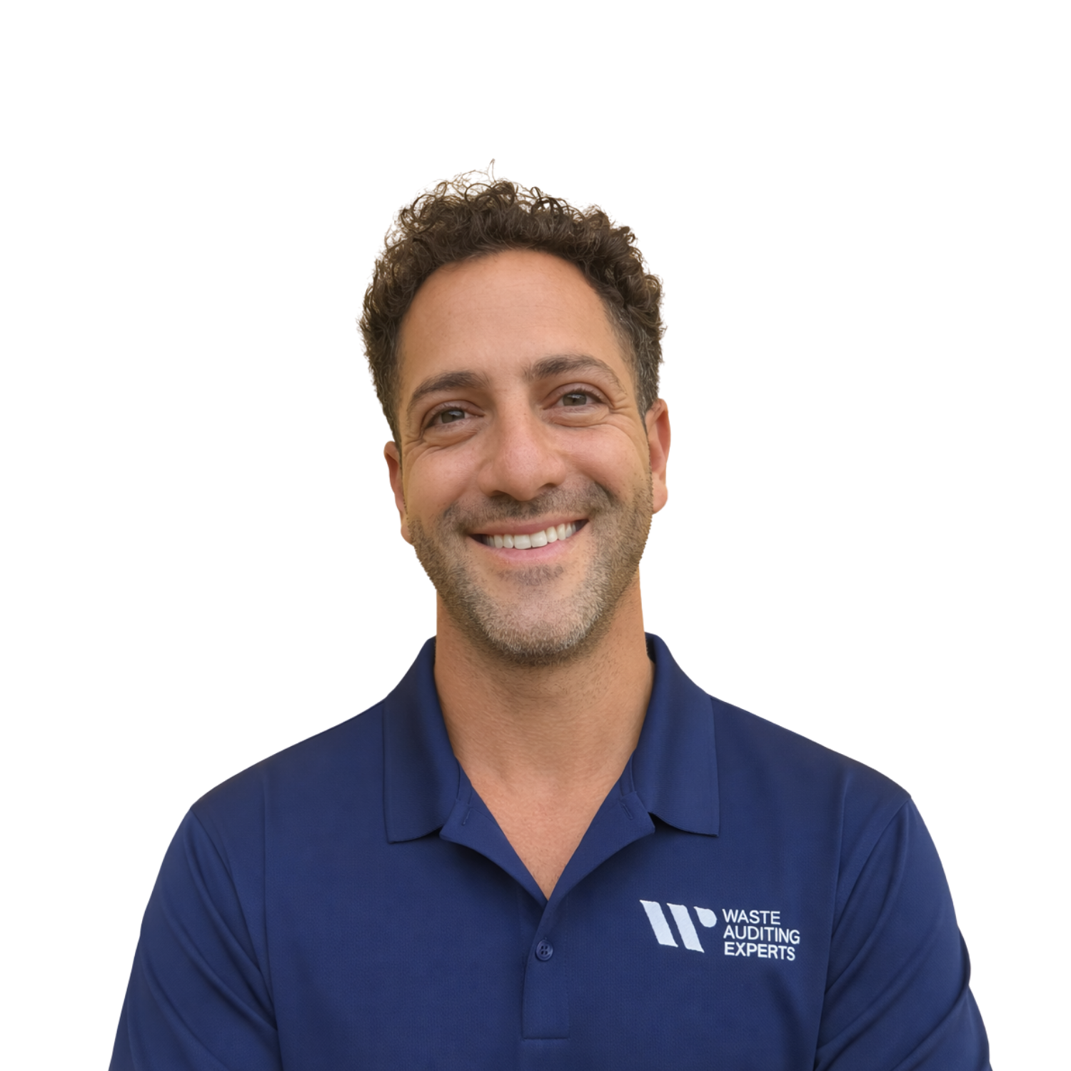 A man with brown hair a blue short-sleeve sweater and beige pants sitting on a cushioned bench against a plain wall with a shadow cast to his right.