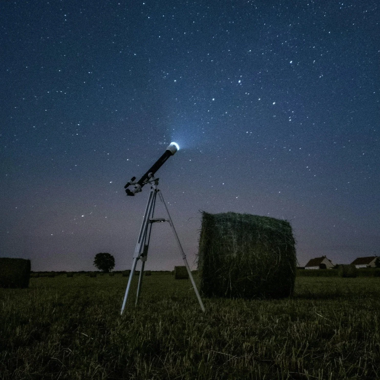 Telescope in front of hay bales and starry sky 