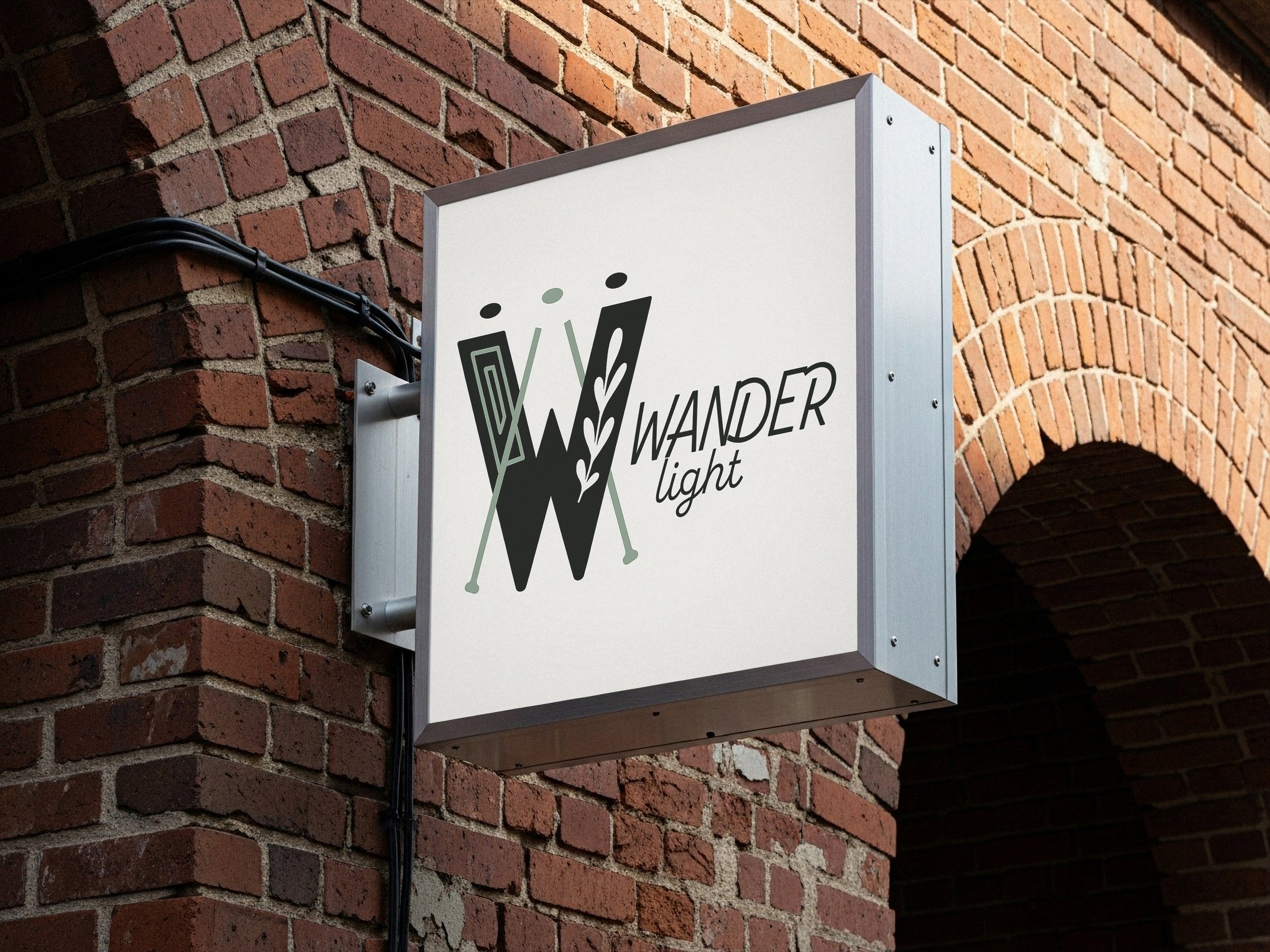 Outdoor sign mounted on brick wall with the logo and text for 'Wander Light' featuring stylized letter 'W' with arrows and leaves.