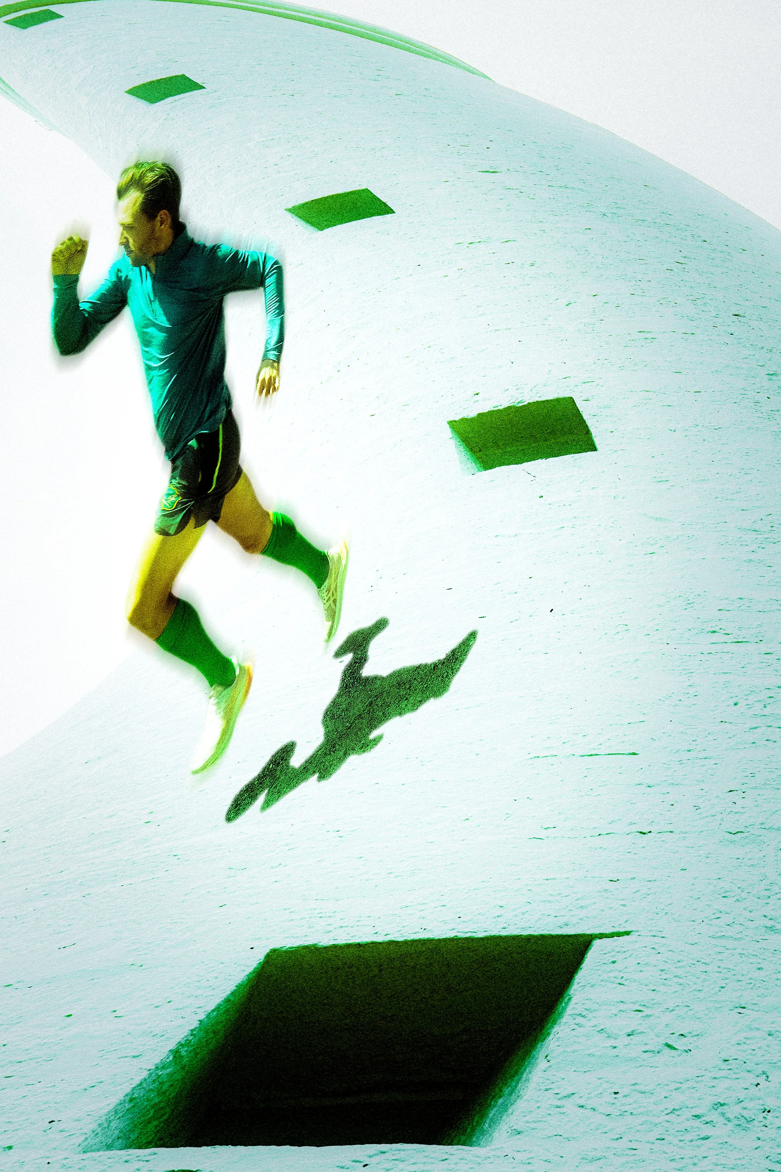A man running on a white track with green square markings and black shadow, viewed from below.