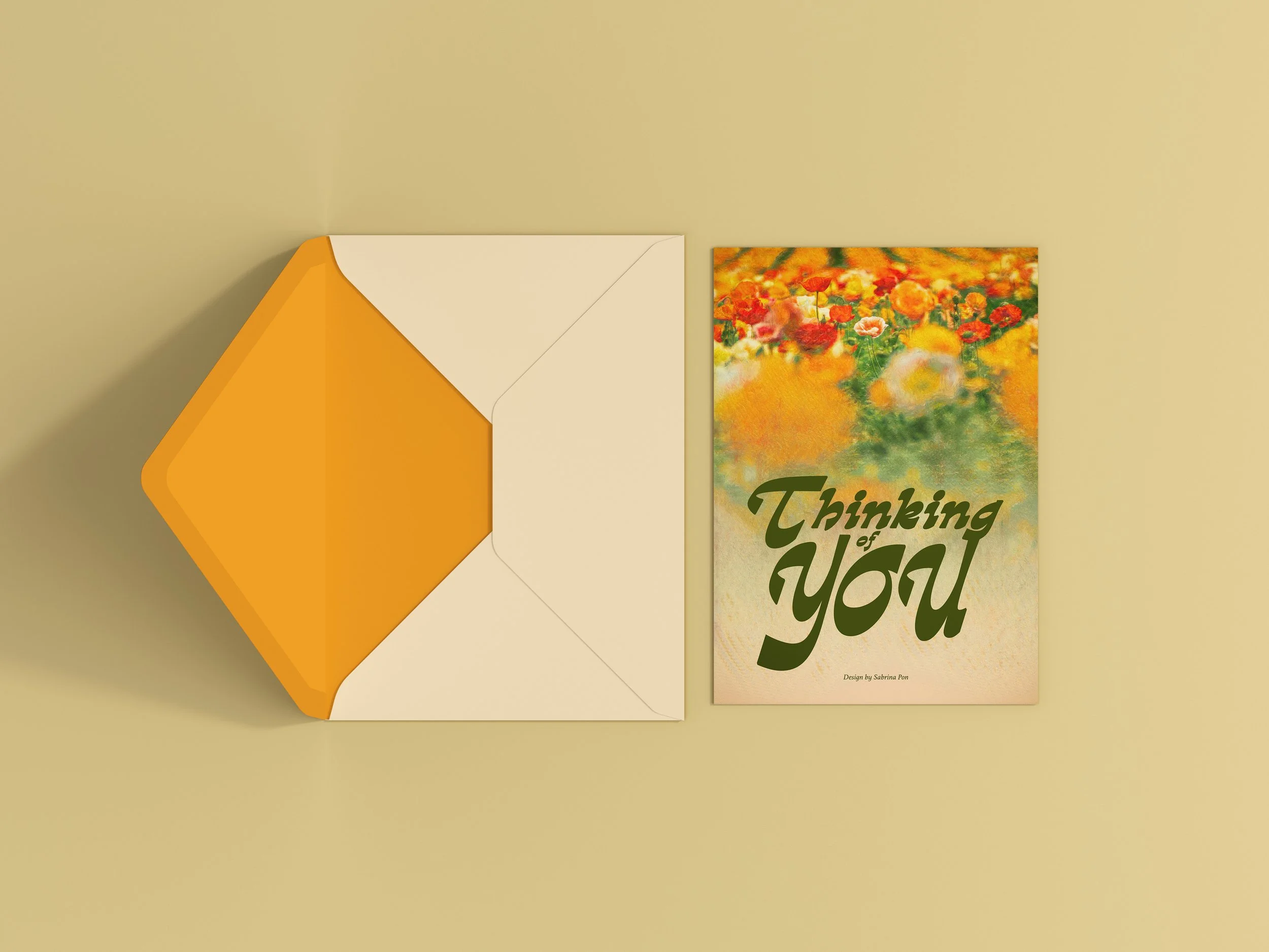 A greeting card with a colorful garden of flowers and the words 'Thinking of You' on it, placed next to an envelope with a yellow interior.