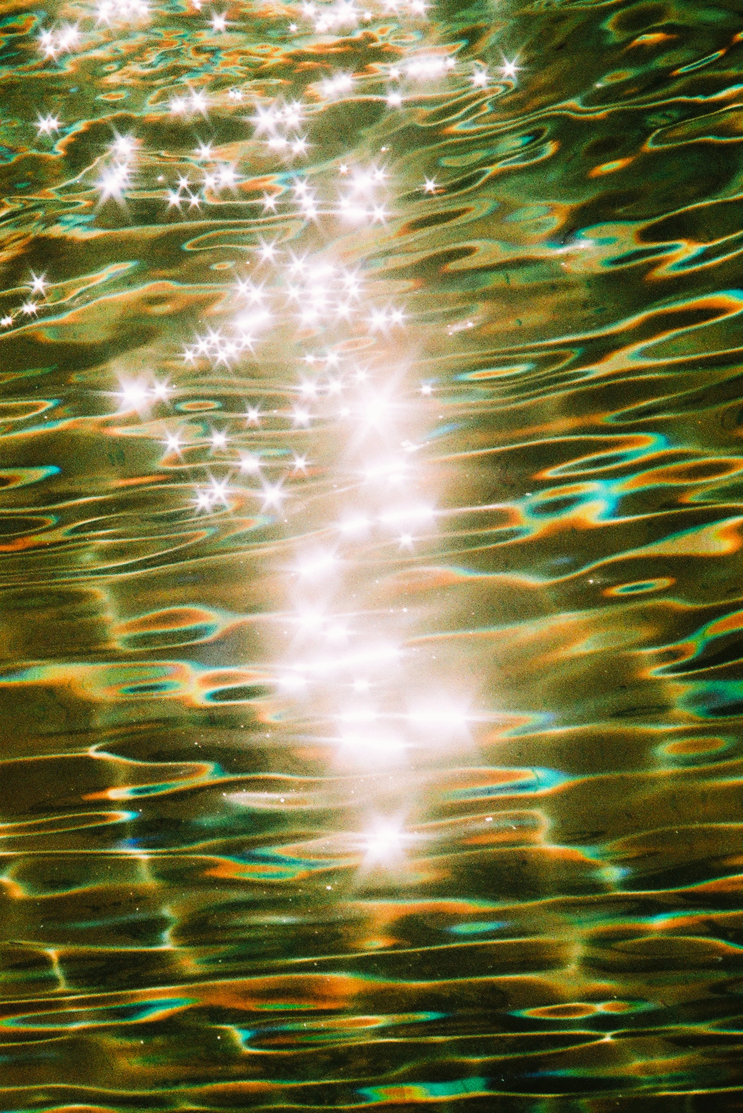 Sunlight reflecting on a rippling body of water creating bright, sparkling highlights and colorful reflections.