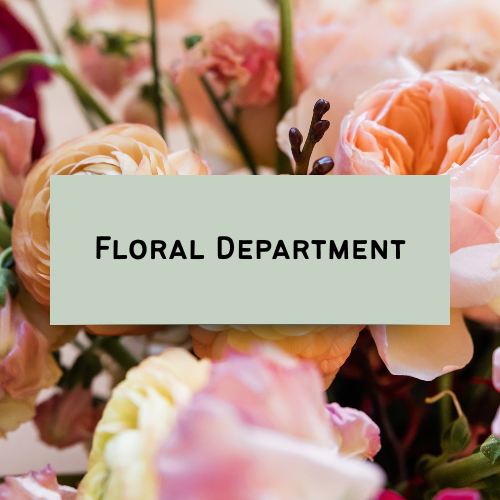 A floral display with a sign that reads 'Floral Department' surrounded by pink and peach roses.