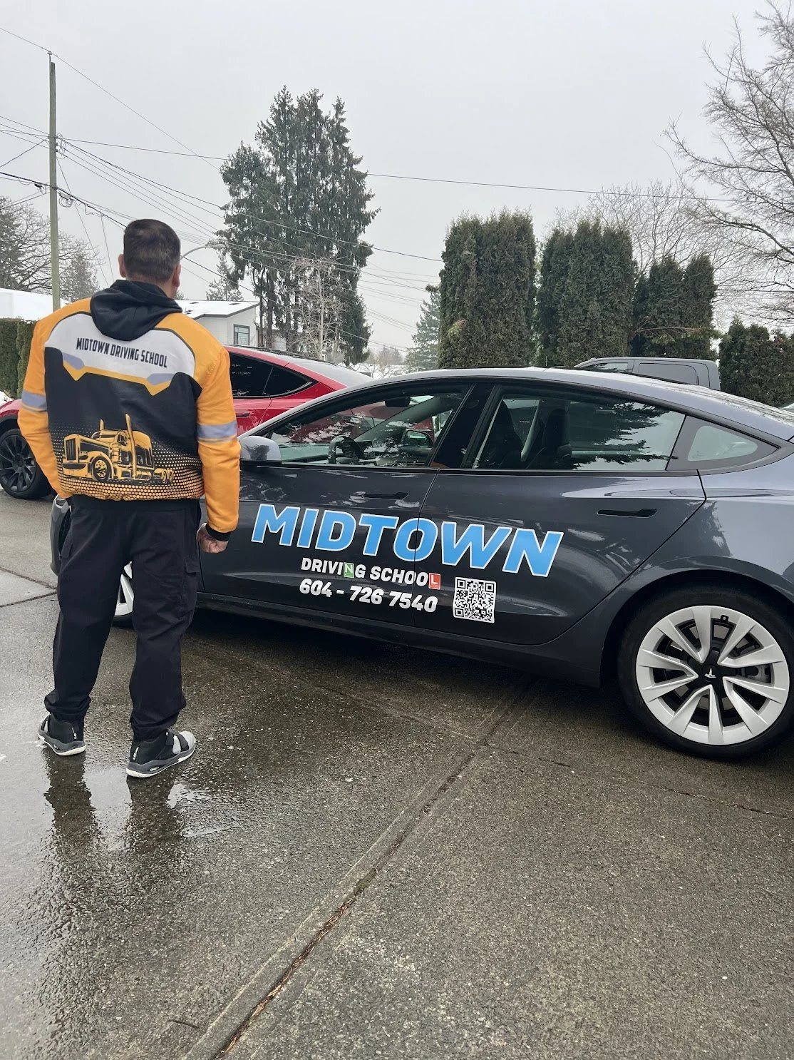 A boy wearing headphones takes a selfie in a room with a brick fireplace, a wall-mounted TV, and a framed picture. He holds an octagonal blue and pink object in his right hand.
