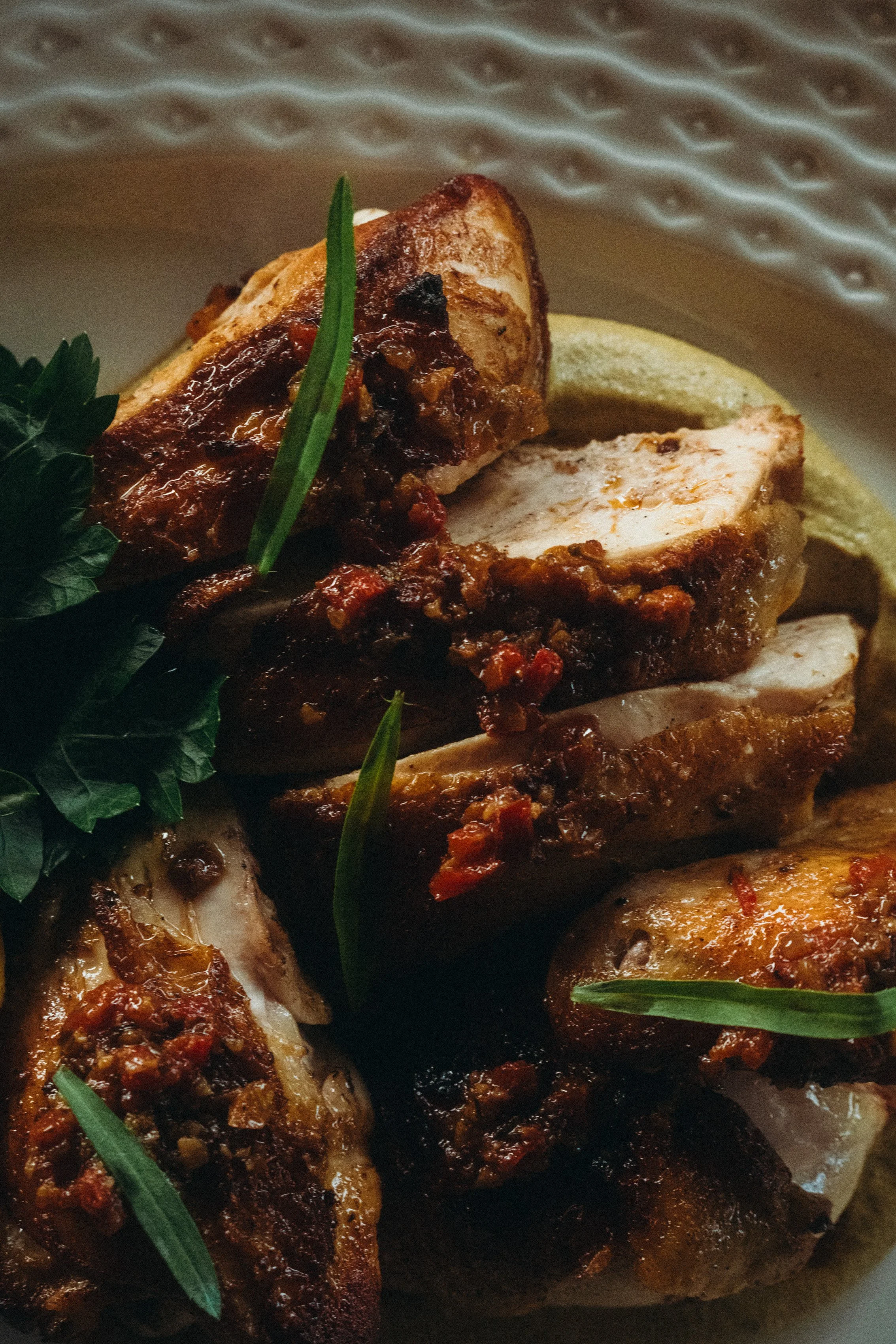 1/2 charcoal chicken. Free range chicken, pistachio tarator, spiced red pepper butter and lemon. Close-up beautiful decorated plate.