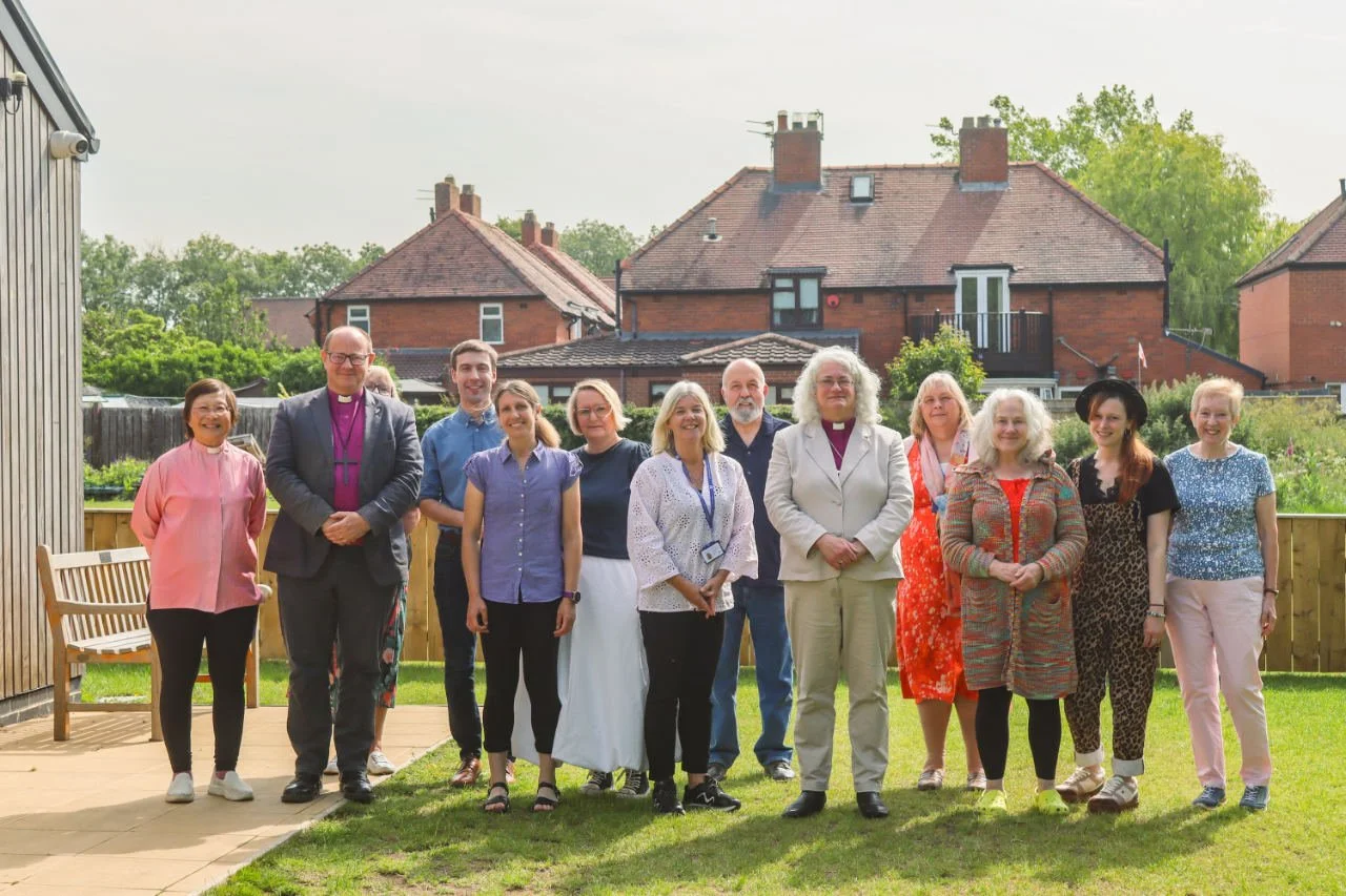 Group of people standing outdoors in a backyard, posing for a photo.