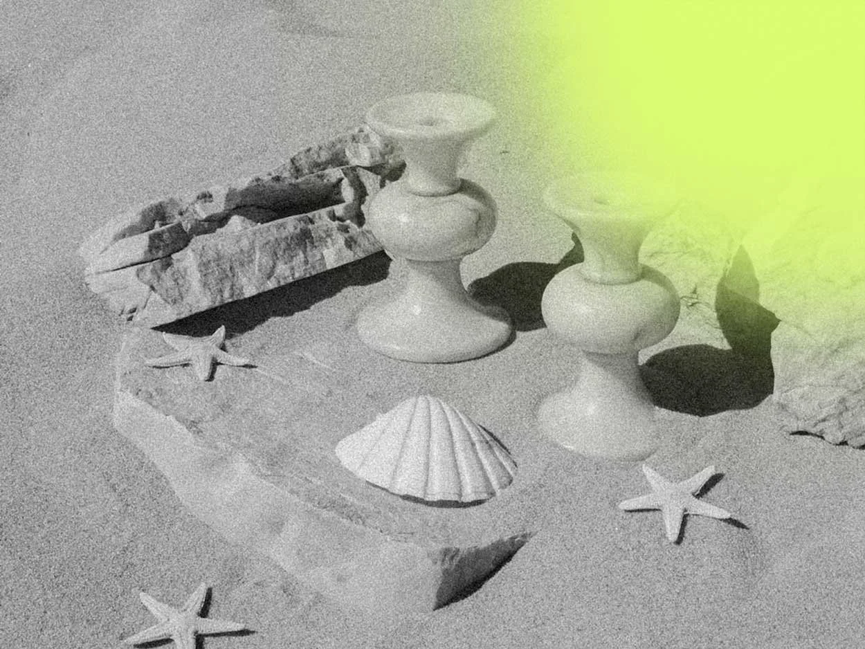Decorative beach-themed items including starfish, shells, and ceramic candleholders on a sandy surface.