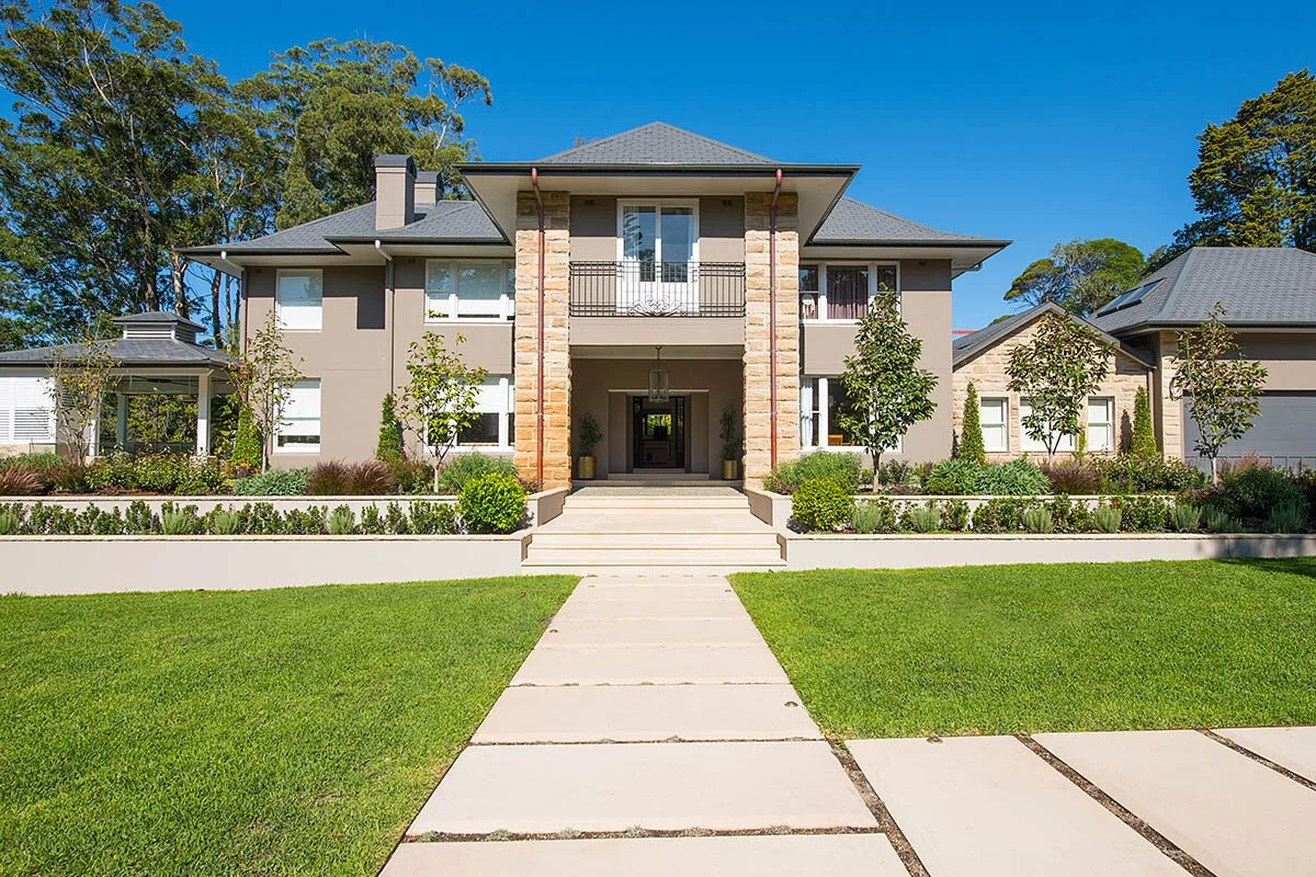 Front view of a modern two-story house with a well-maintained lawn, walkway, and landscaped garden.
