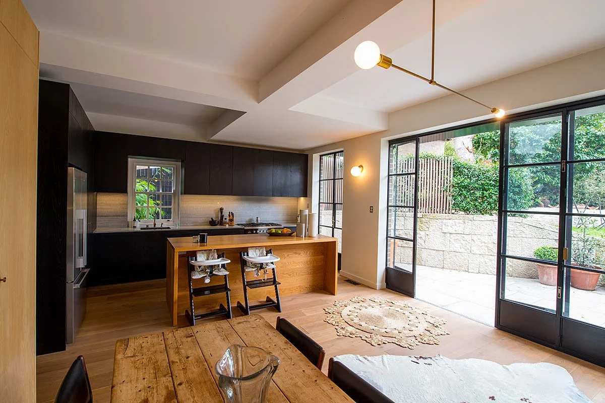 Modern open-plan kitchen and dining area with large glass doors opening to a patio and garden.