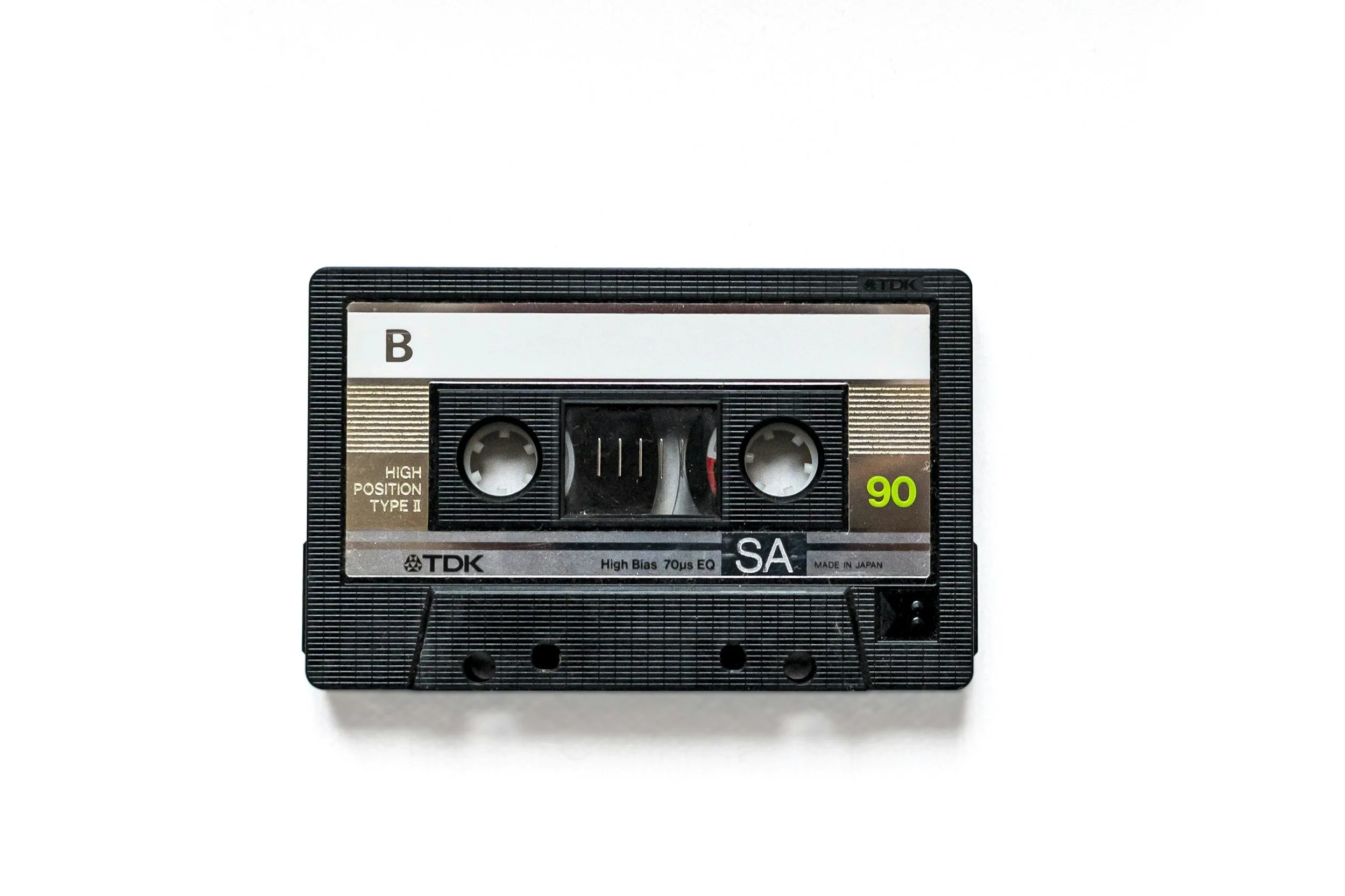 A black audio cassette tape with silver and green labels, labeled 'TDK', 'SA', and '90 minutes' on a white background.