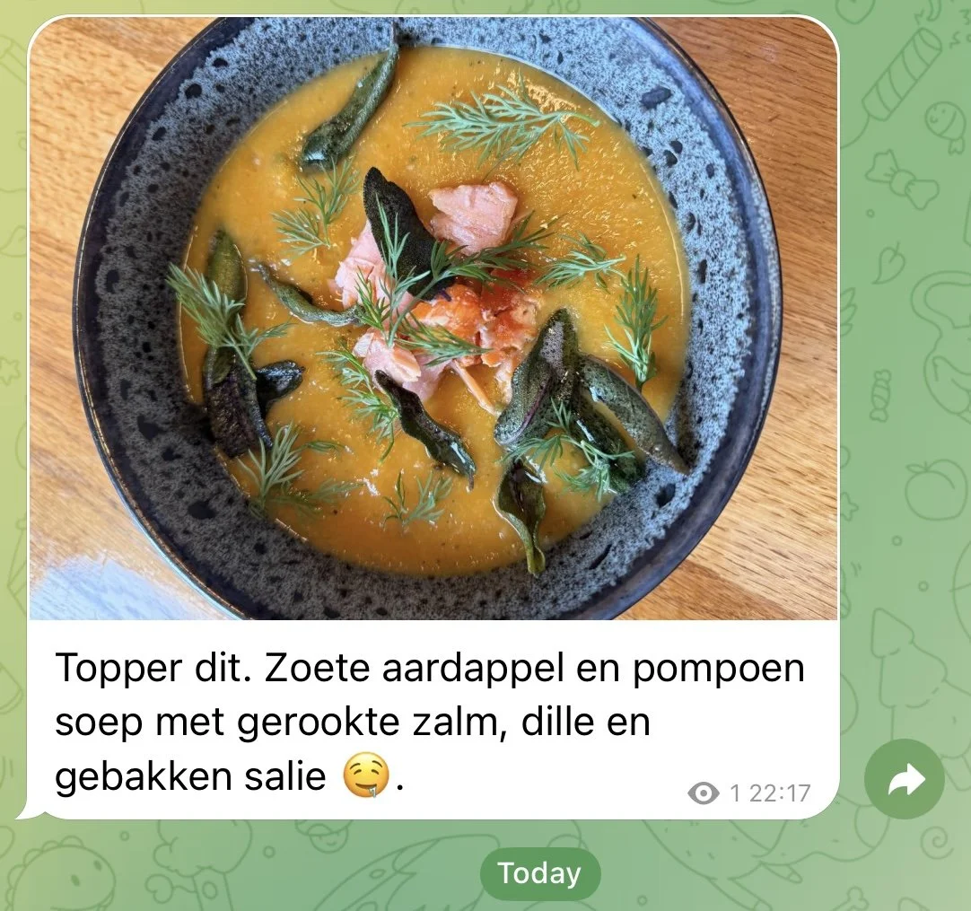 A bowl of sweet potato and pumpkin soup topped with smoked salmon, dill, and fried salie leaves, garnished with fresh dill herbs.