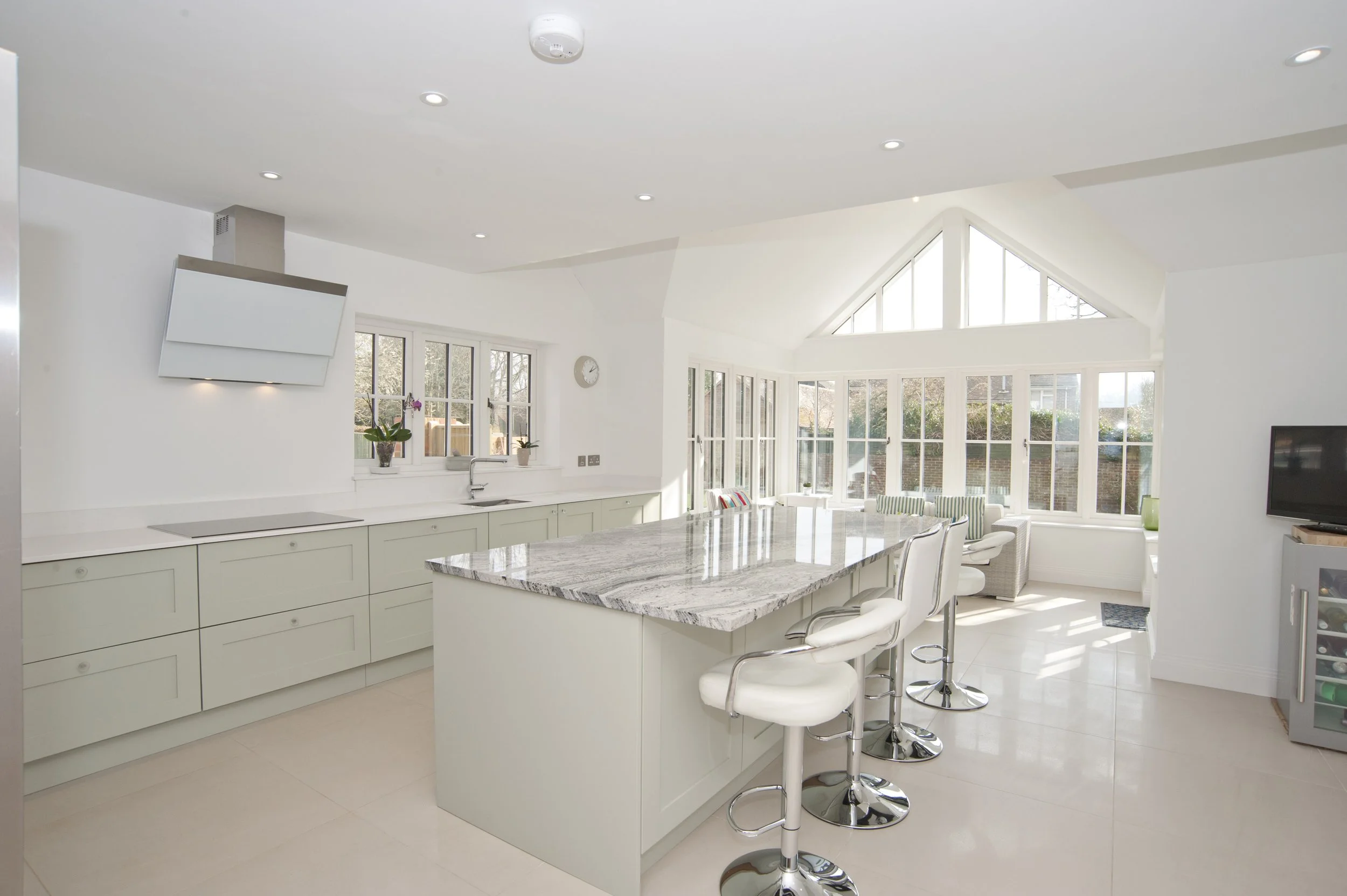 Bright, modern kitchen with white cabinetry, a large marble island, and numerous windows letting in natural light.