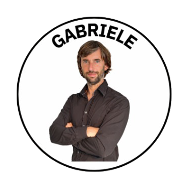 A man with shoulder-length brown hair and a beard, wearing a dark button-up shirt, posing with arms crossed inside a circular frame with the name 'GABRIELE' at the top.