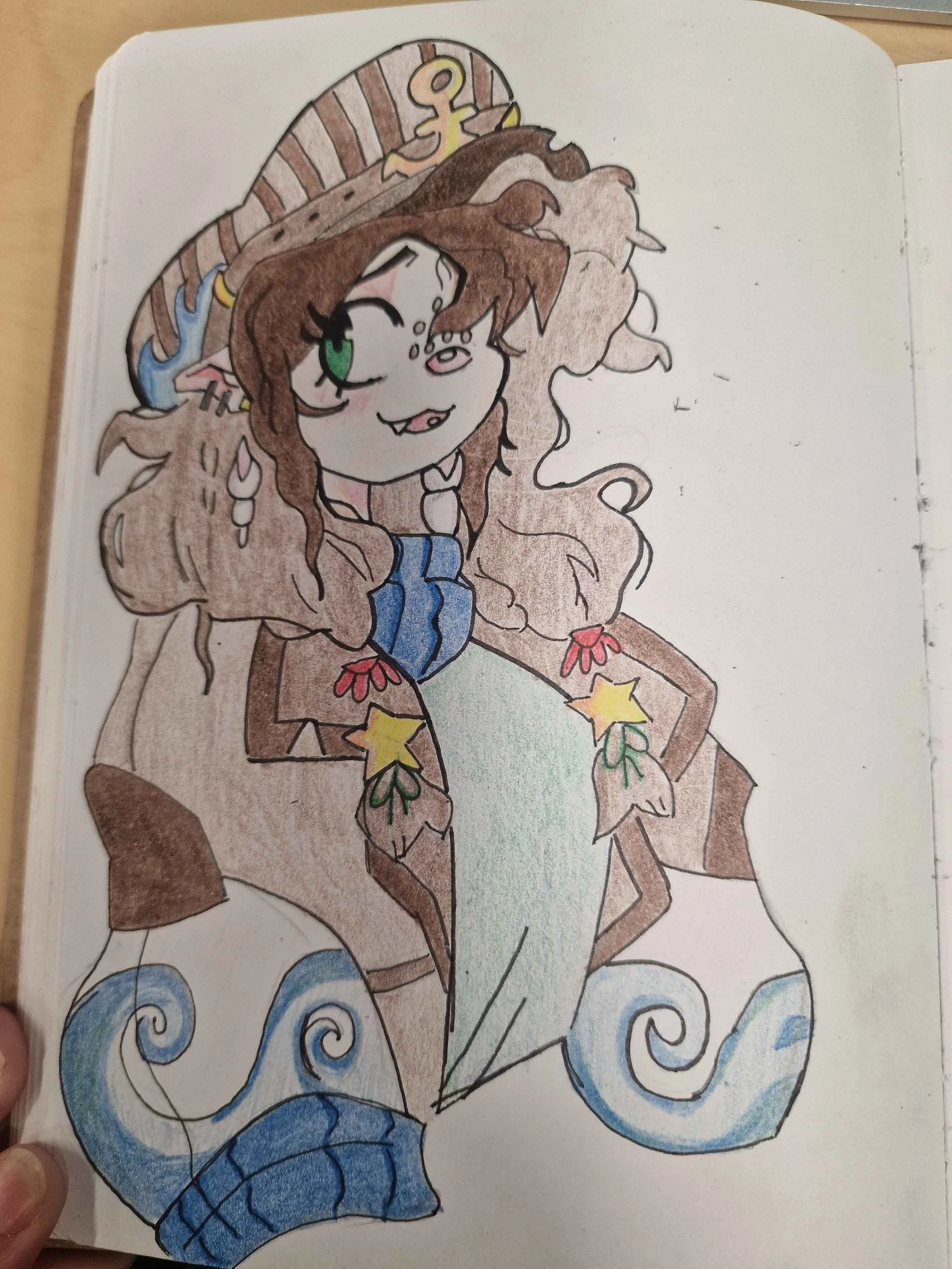 Hand-drawn colored illustration of a cartoon pirate mermaid with long curly brown hair, green eye, and a pirate hat, partially emerging from stylized blue waves.