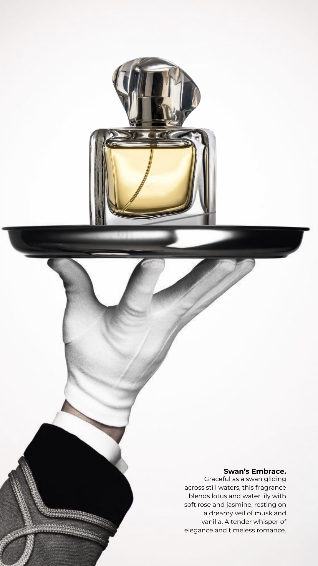 A hand wearing a white glove holding a black tray with a glass perfume bottle on top. The perfume bottle is transparent with a gold-colored liquid inside and a shiny silver cap. There is a short description of the perfume called "Swan's Embrace" in t
