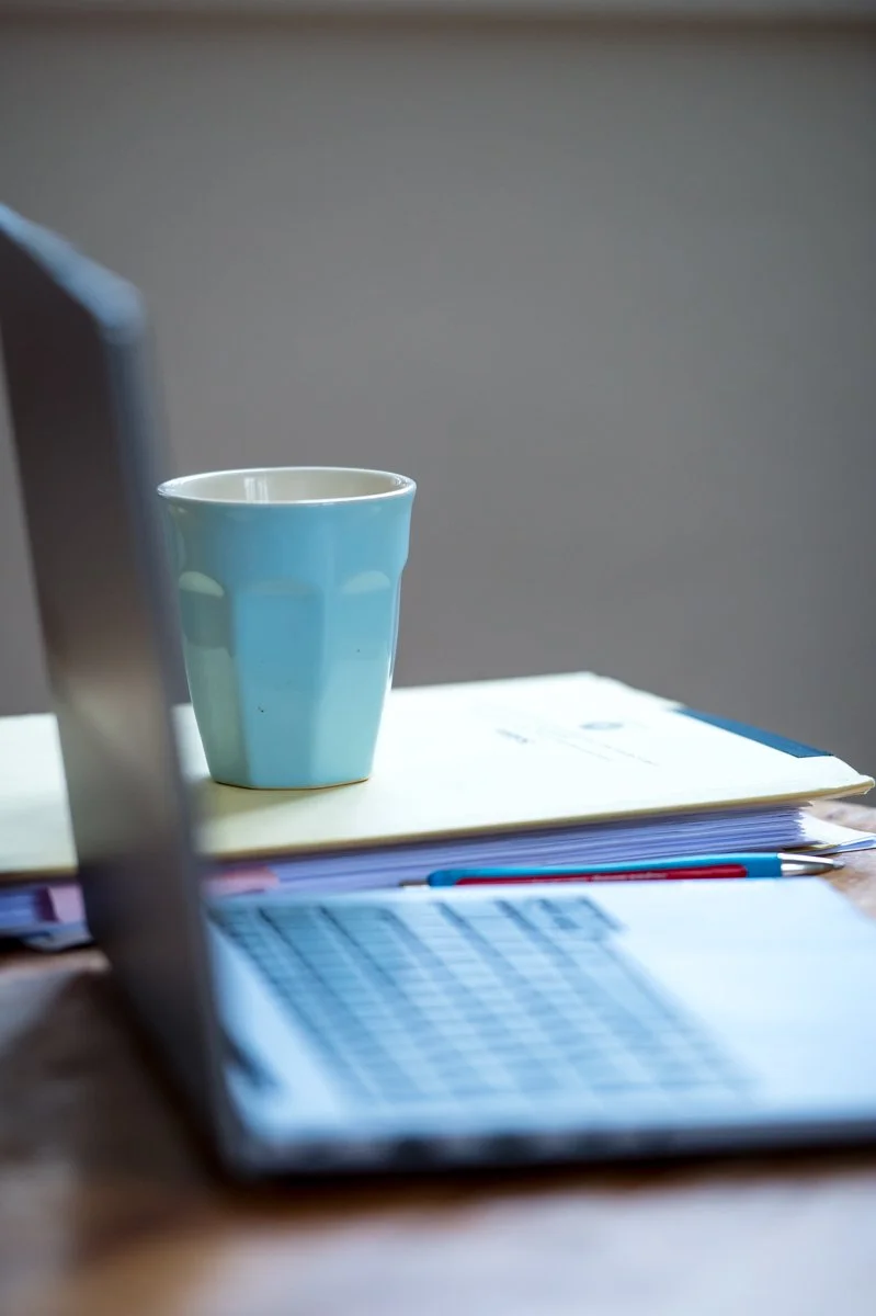 Büroarbeitsplatz mit Laptop, Kaffeetasse und Notizblock