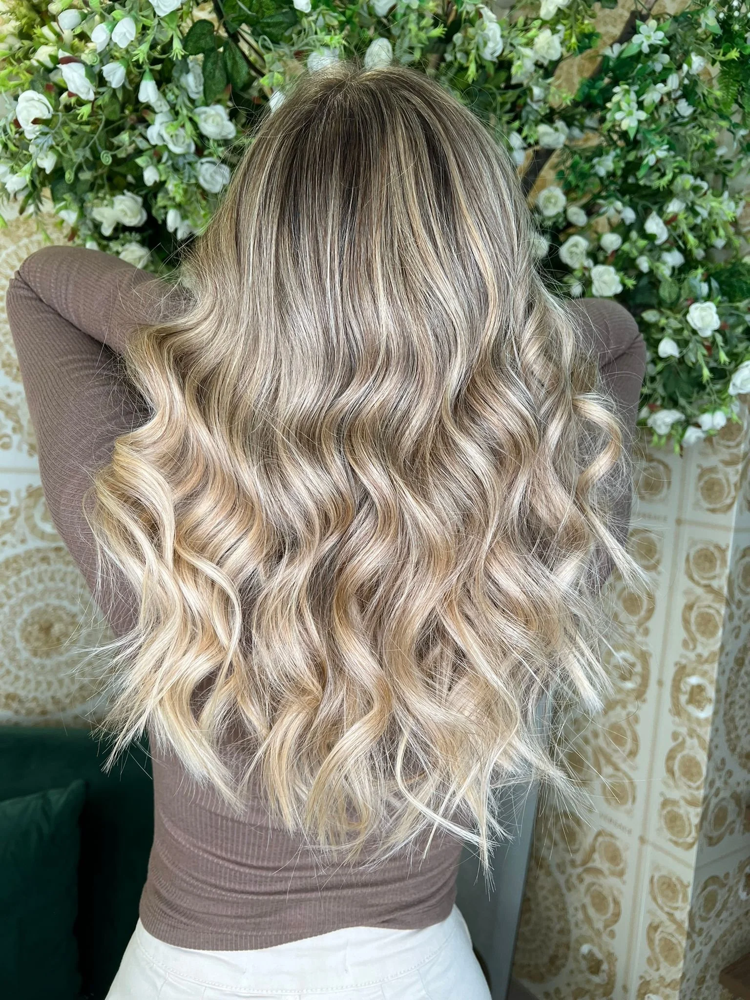 Cabelos cacheados com ondulação solta, em tom loiro com mechas luzes, vistos de trás. Trabalho realizado por Bi Ribeiro Hairstylist