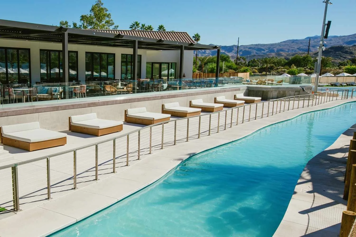 Interior of a building under construction or renovation with large windows, modern chandeliers, and a cluttered area with construction materials, wood pallets, and boxes.