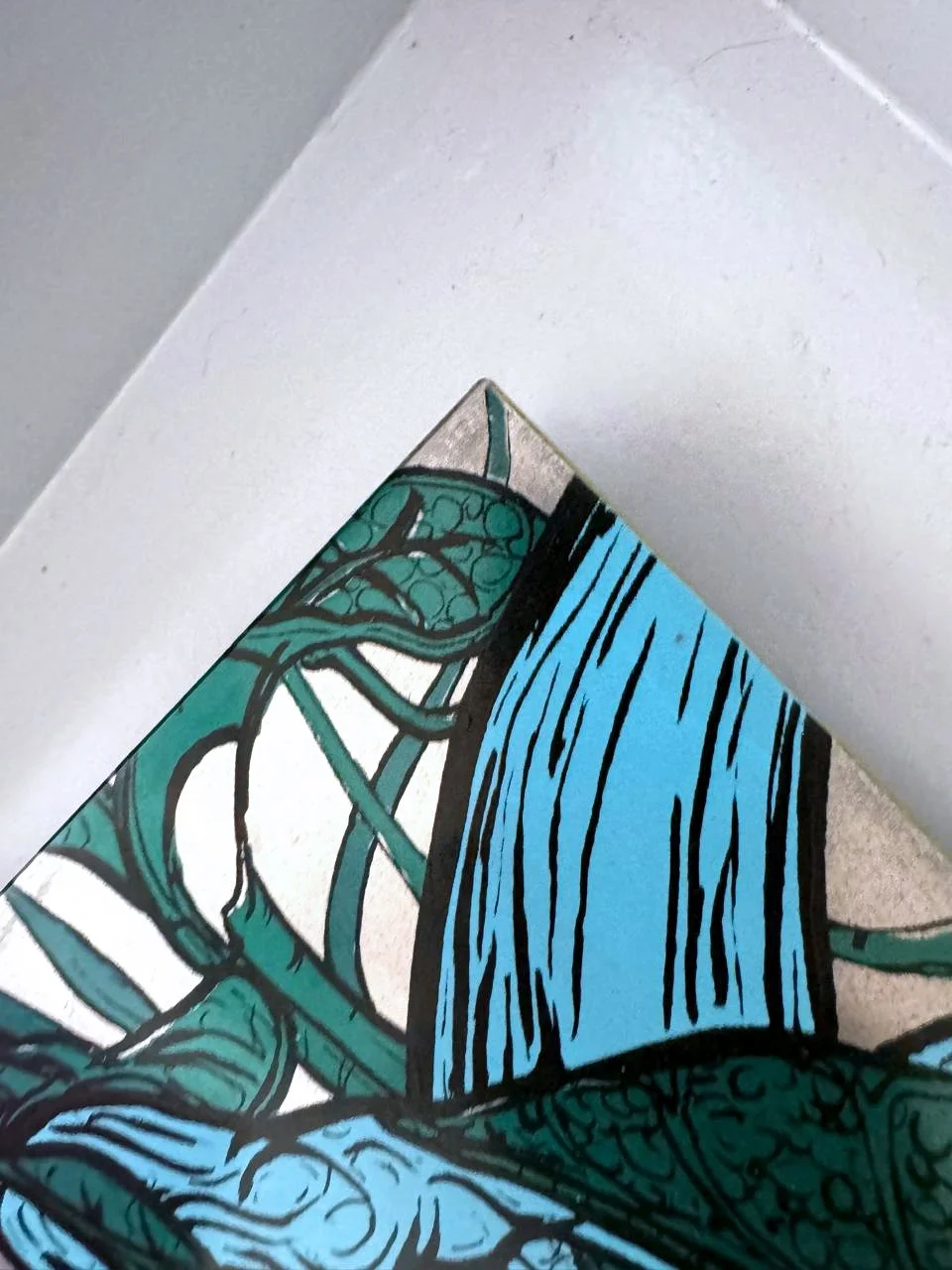 Close-up of a colorful comic book corner with blue, black, and green ink lines on paper.