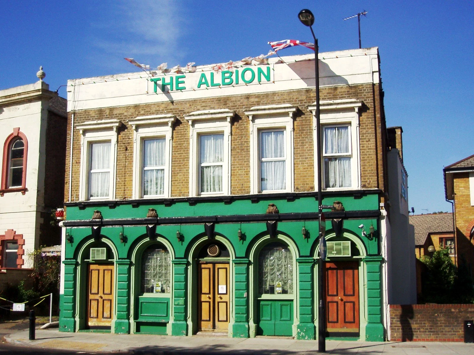 The Albion pub building with green and brown facade, three doors, arched windows, and a sign reading 'THE ALBION' on top.