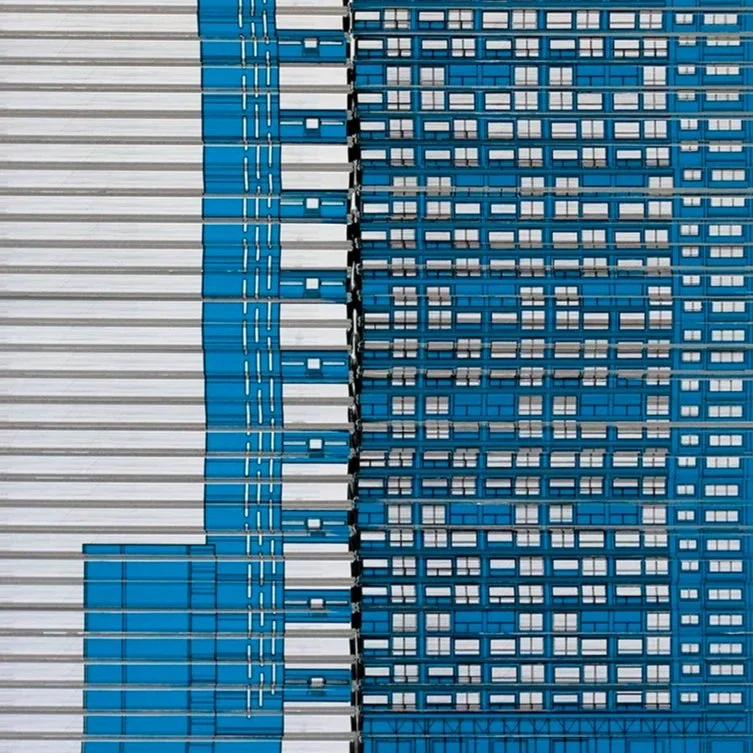 Close-up of a modern building's exterior with blue and white panels and numerous windows.