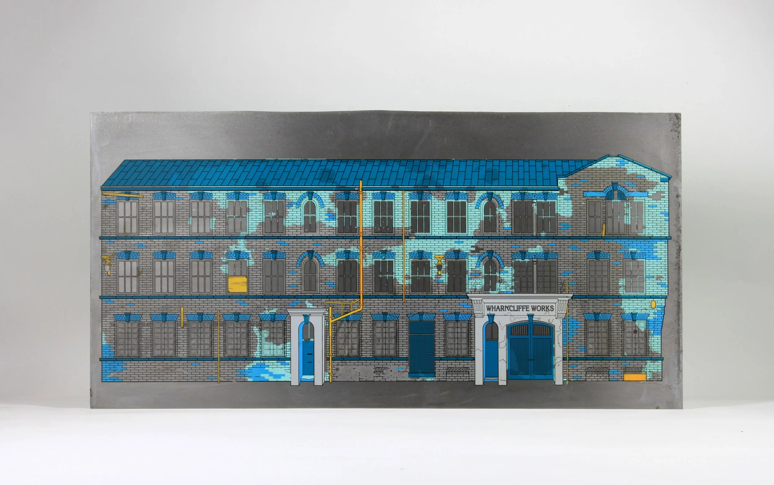 Illustration of a building with a sign that reads 'Wharncliffe Works,' featuring multiple stories, large windows, a blue roof, and blue and gray brick walls, with some yellow and orange pipes and accents.