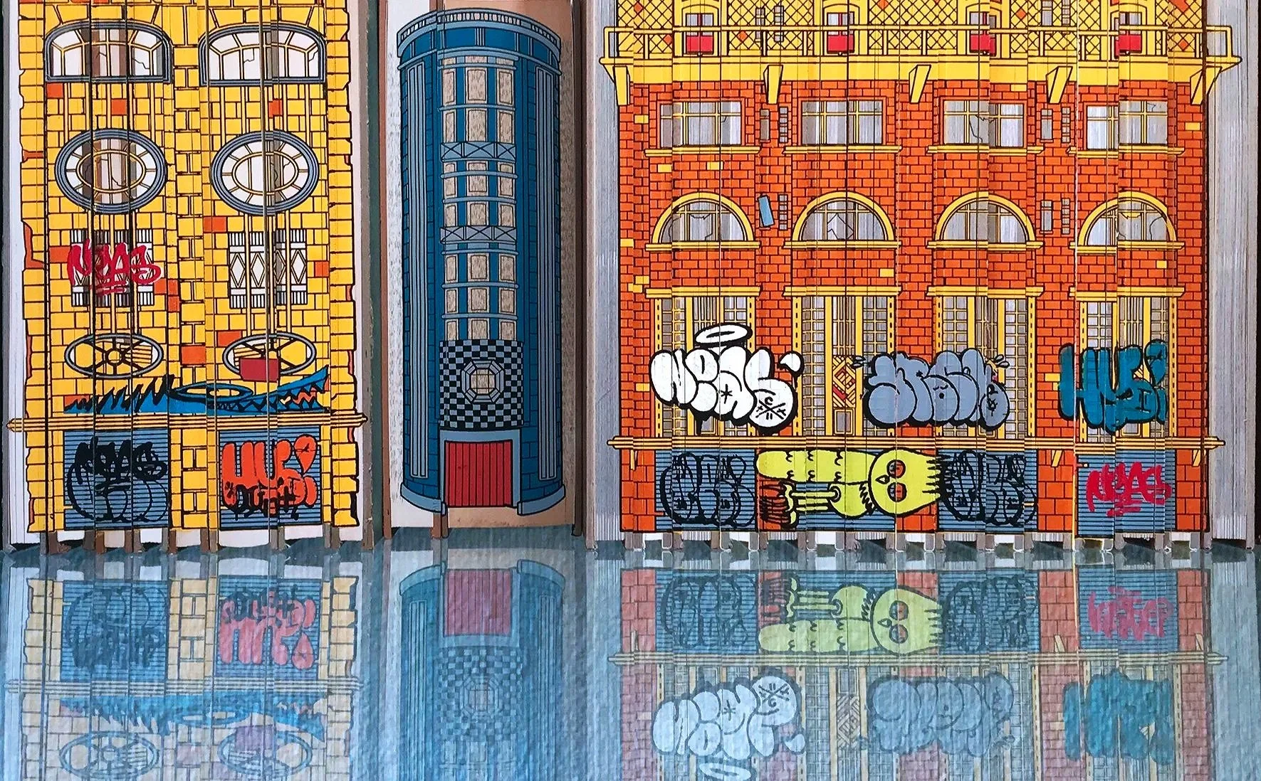 Three colorful buildings with graffiti on the lower parts are reflected in a shiny floor. The buildings are yellow, blue, and orange, each with distinct architectural details.