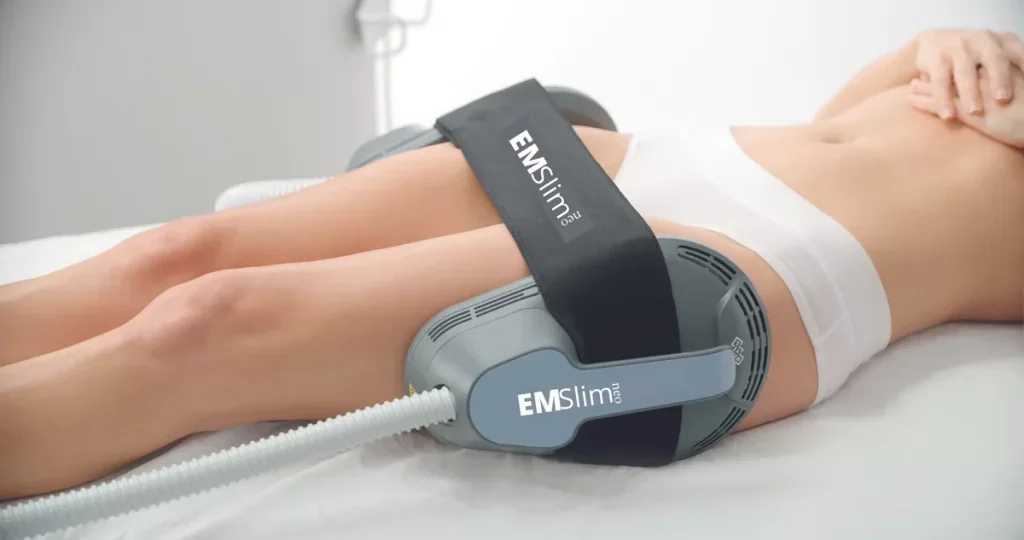 Person lying on a bed with EMSlim Neo applicator strapped to their thighs for body contouring or muscle stimulation.