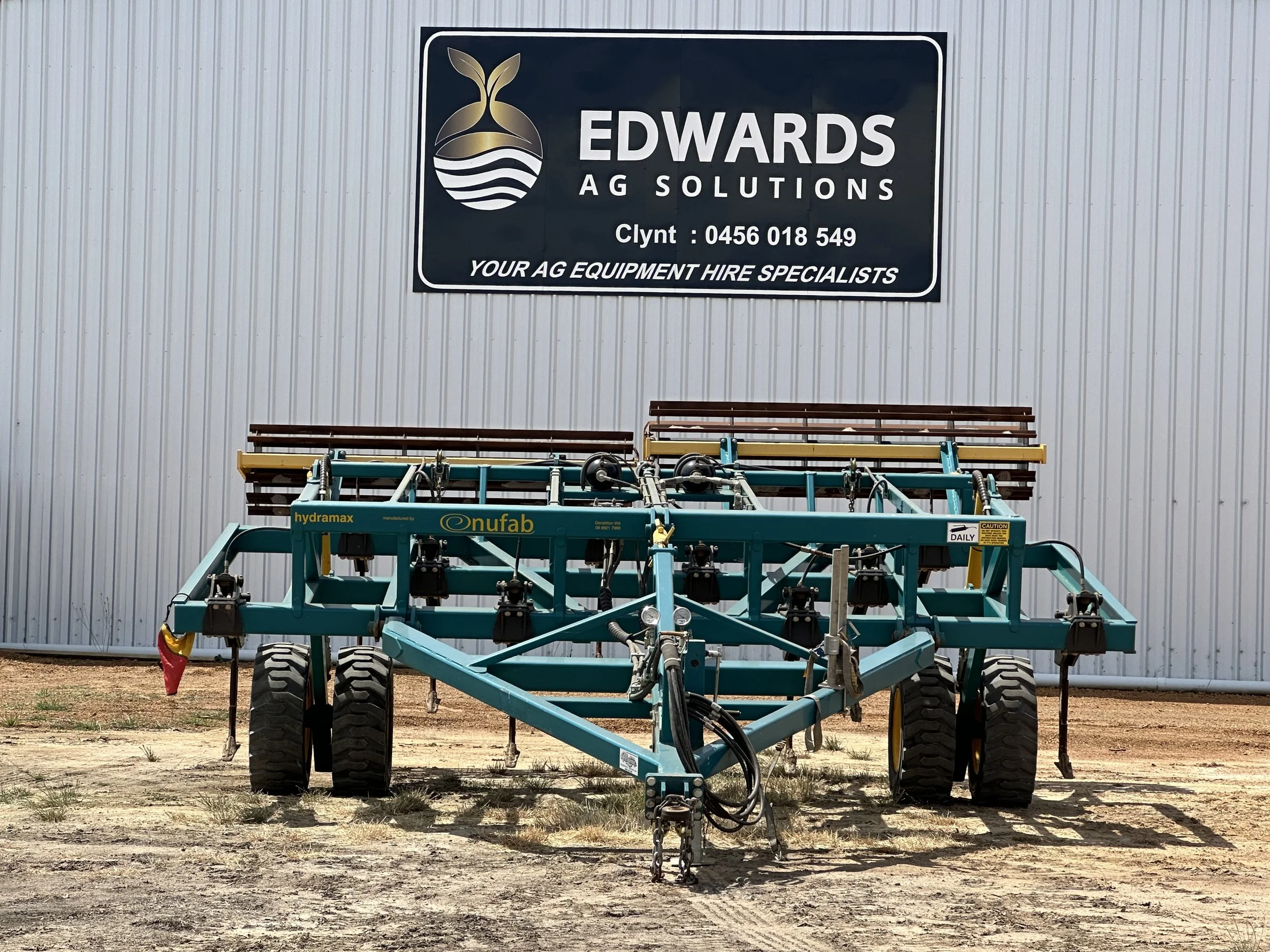 Agricultural equipment in front of a building with a sign for Edwards AG Solutions