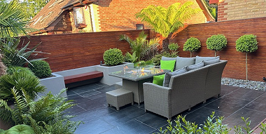 Contemporary courtyard garden with built-in seating, paving and lush planting in Hordle.
