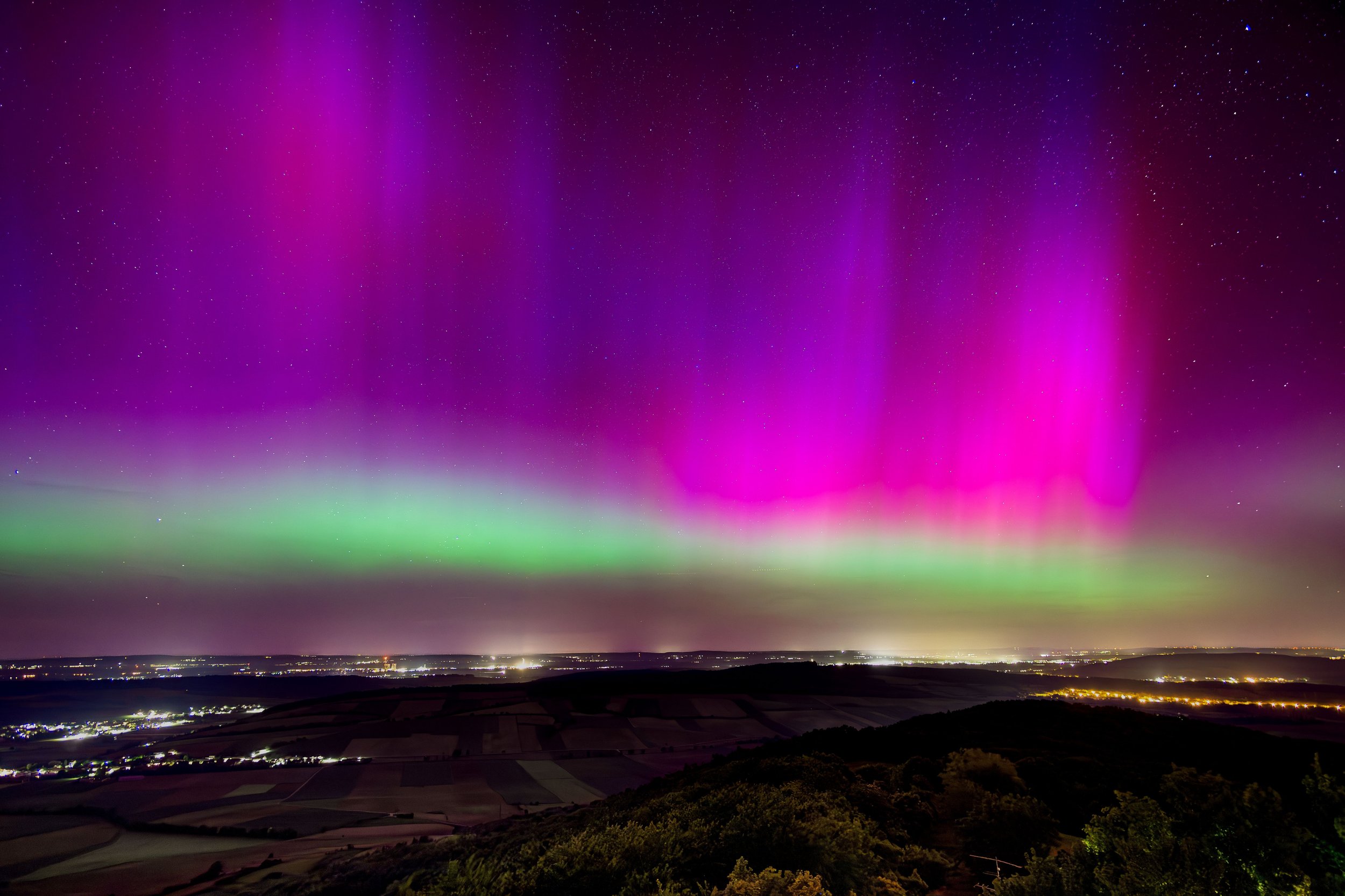 Nordlichter am Nachthimmel über einer ländlichen Landschaft