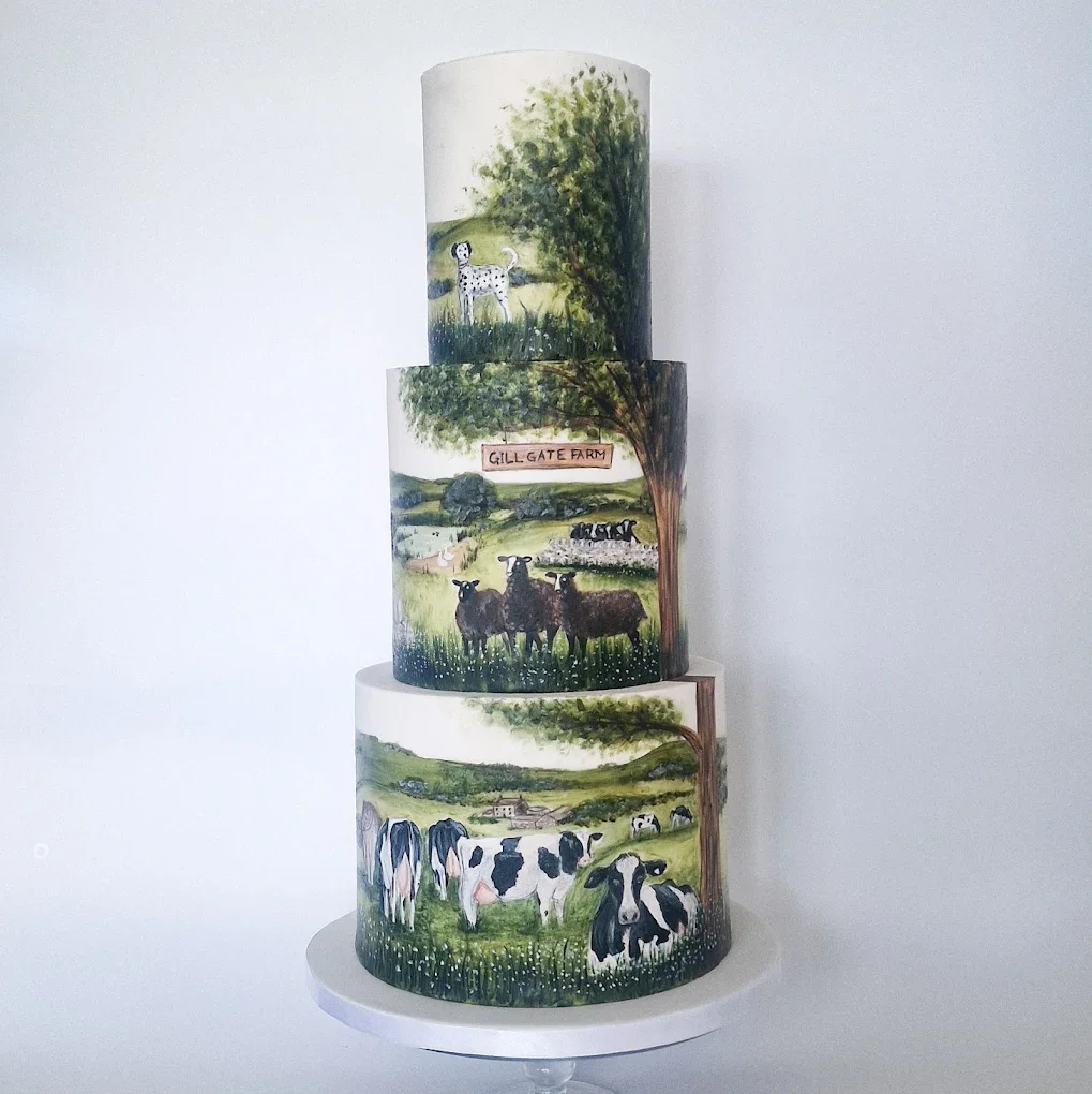 Three-tiered cake decorated with hand-painted pastoral farm scenes, including a Dalmatian dog, cows, sheep, and a sign reading 'GILL GATE FARM', set against a white background.